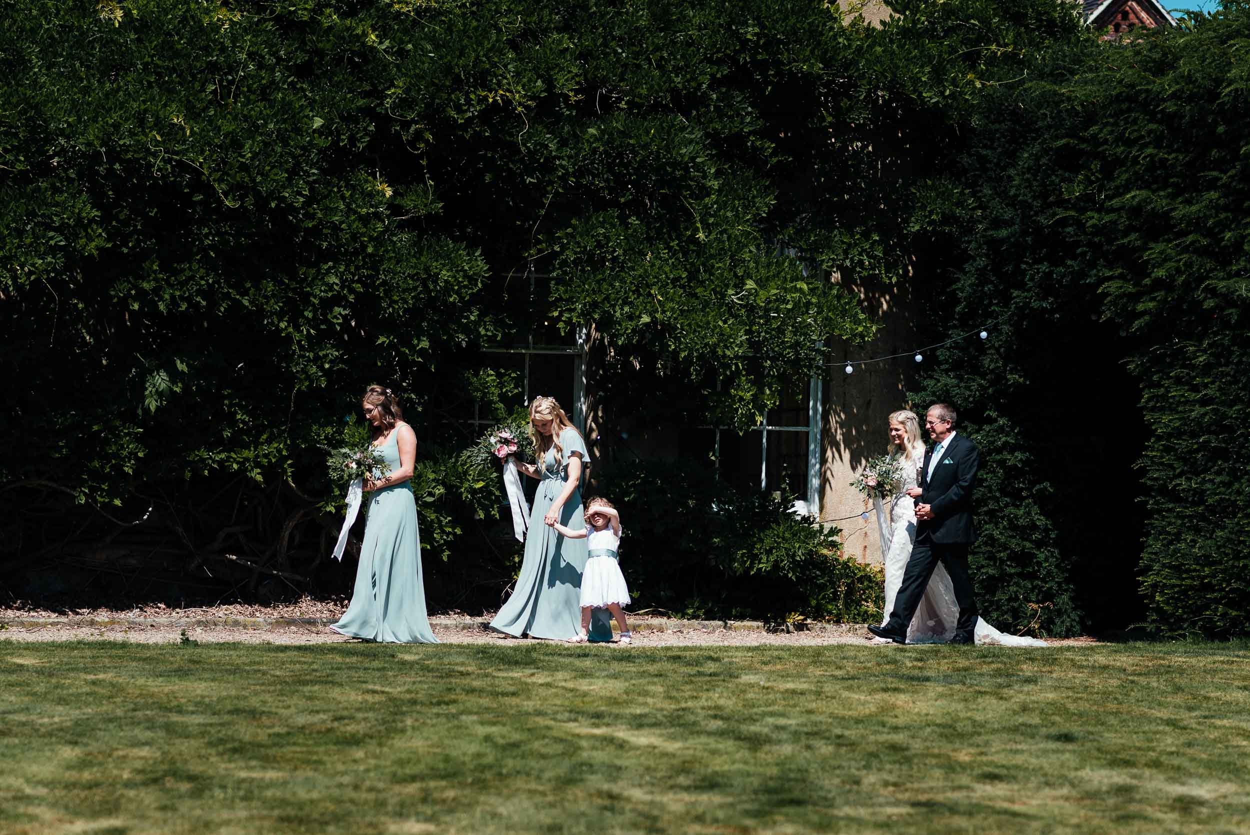 bride walking with her father and bridesmaids