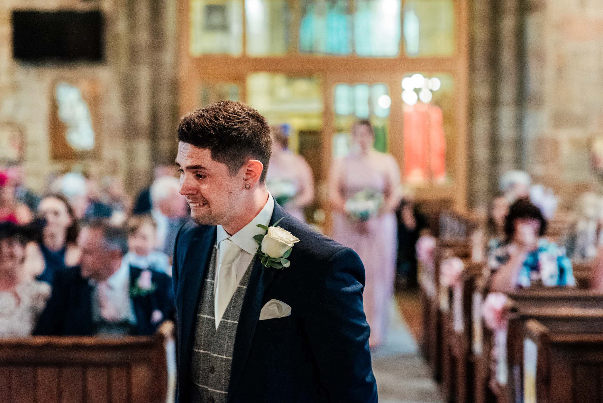 emotional groom as he watches his bride walking down the aisle