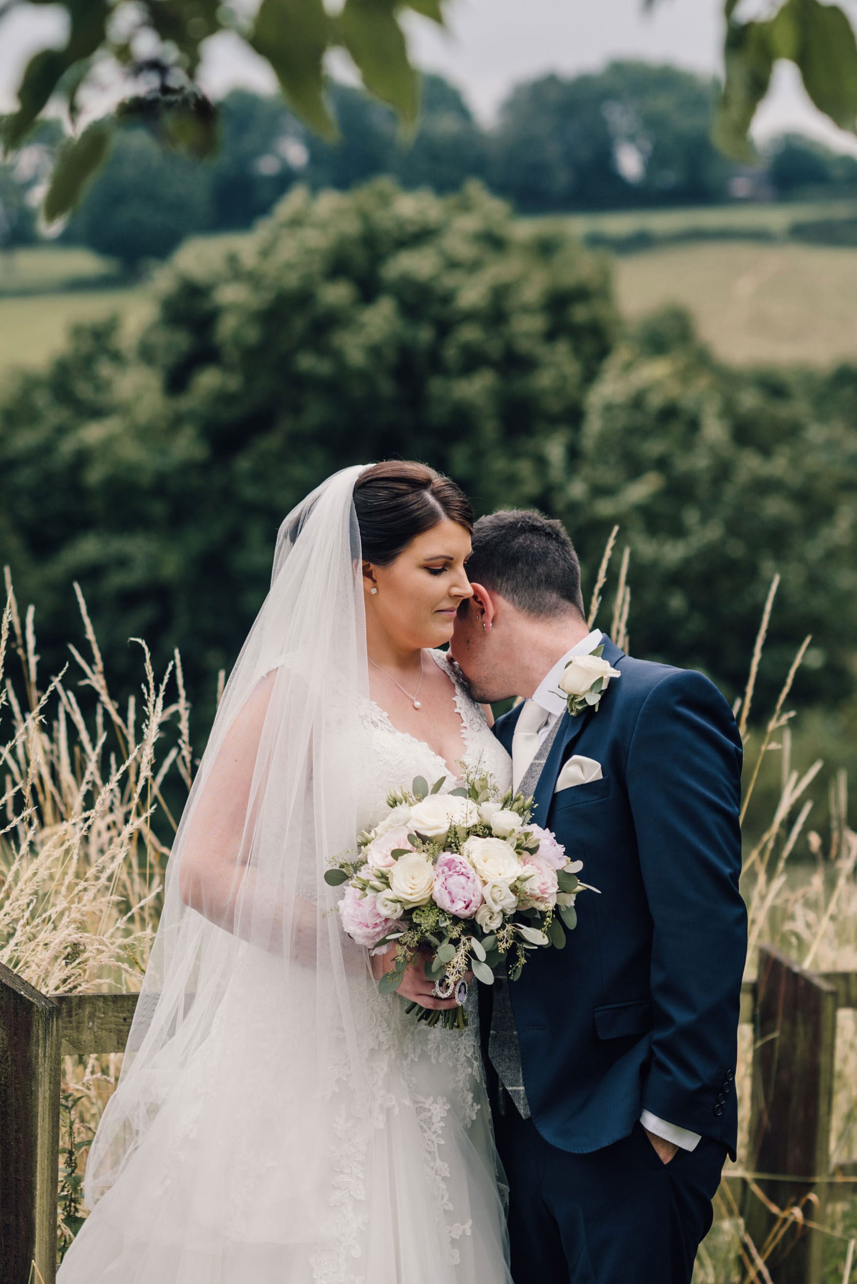 groom gives his bride a tender kiss on the shoulder