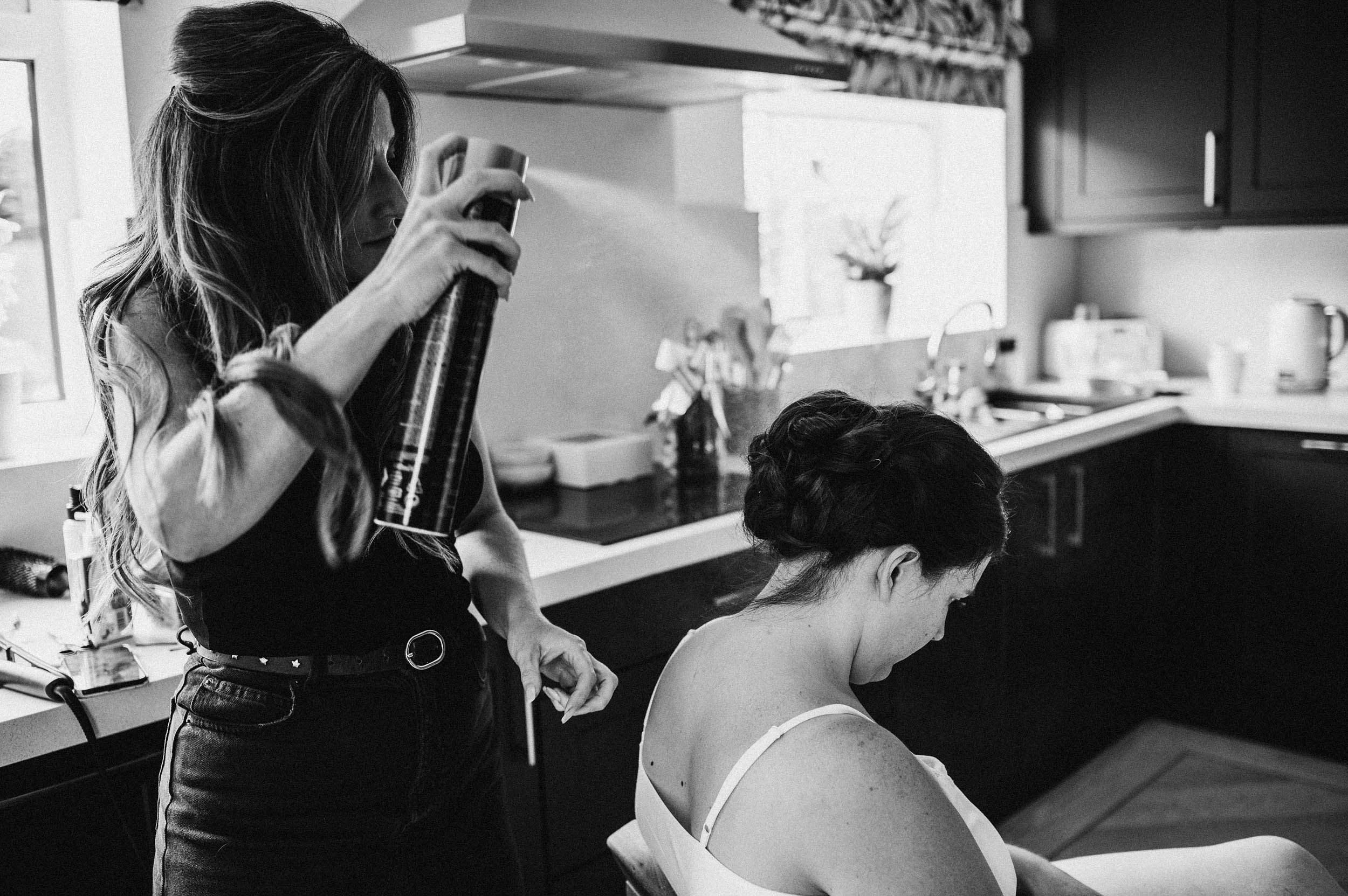 hair dresser spraying hair spray on the brides hair