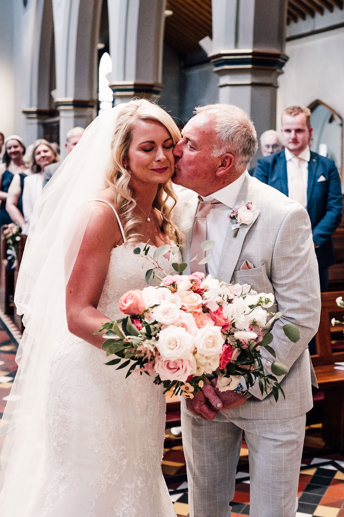 father kisses bride on the cheek