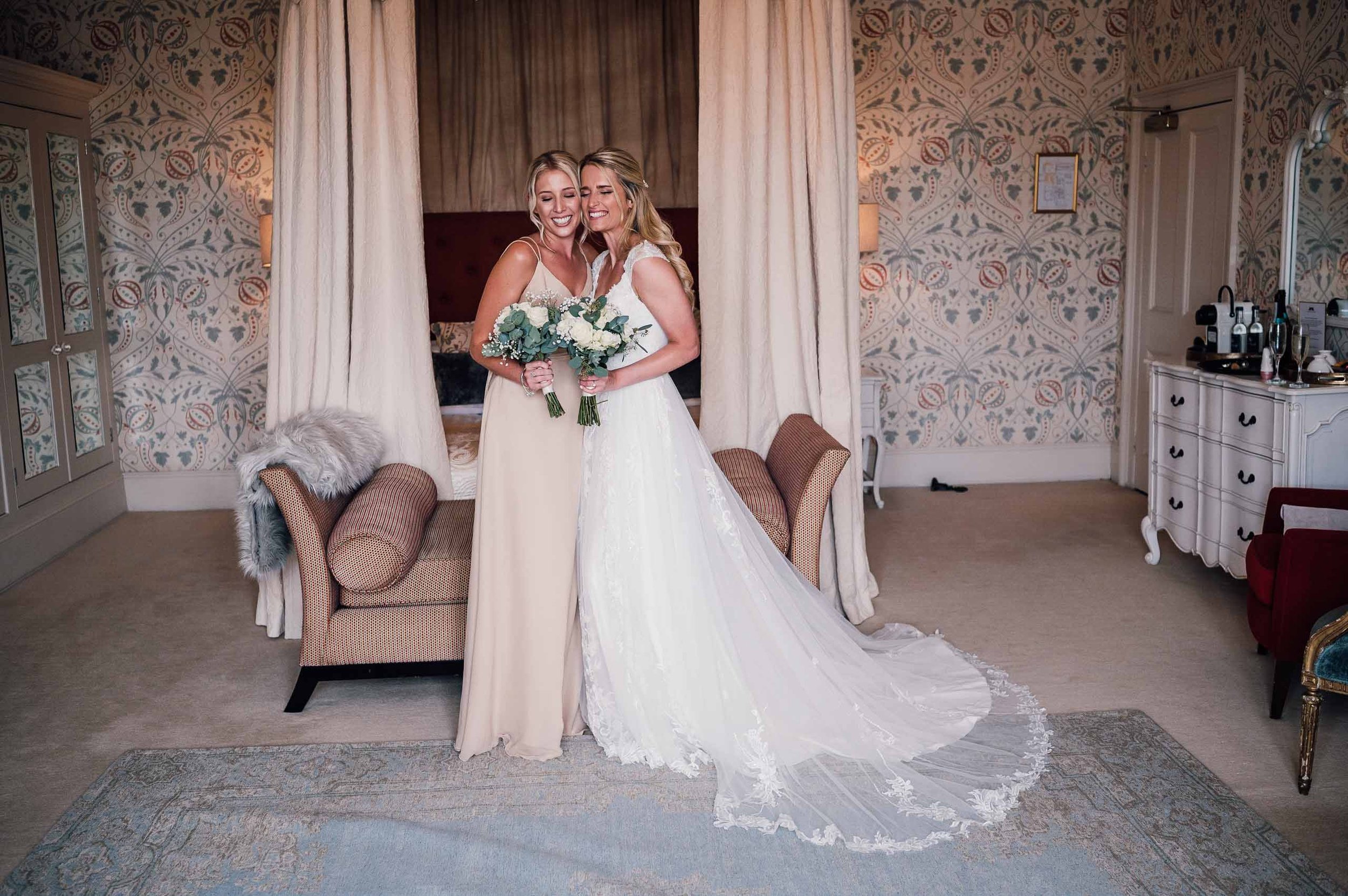 Bride and bridesmaid hugging in the bridal suite at Hodsock Priory