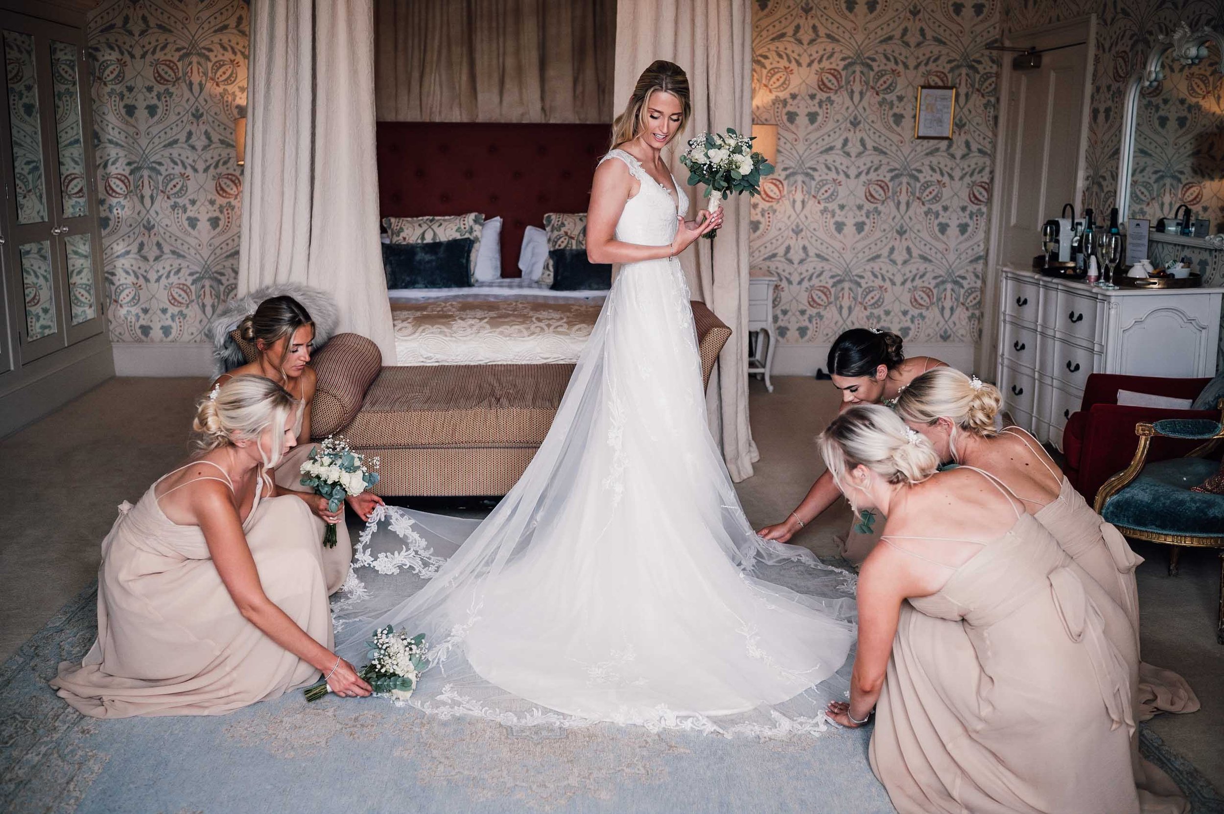 Bridesmaids helpin the bride with her wedding dress at Hodsock Priory