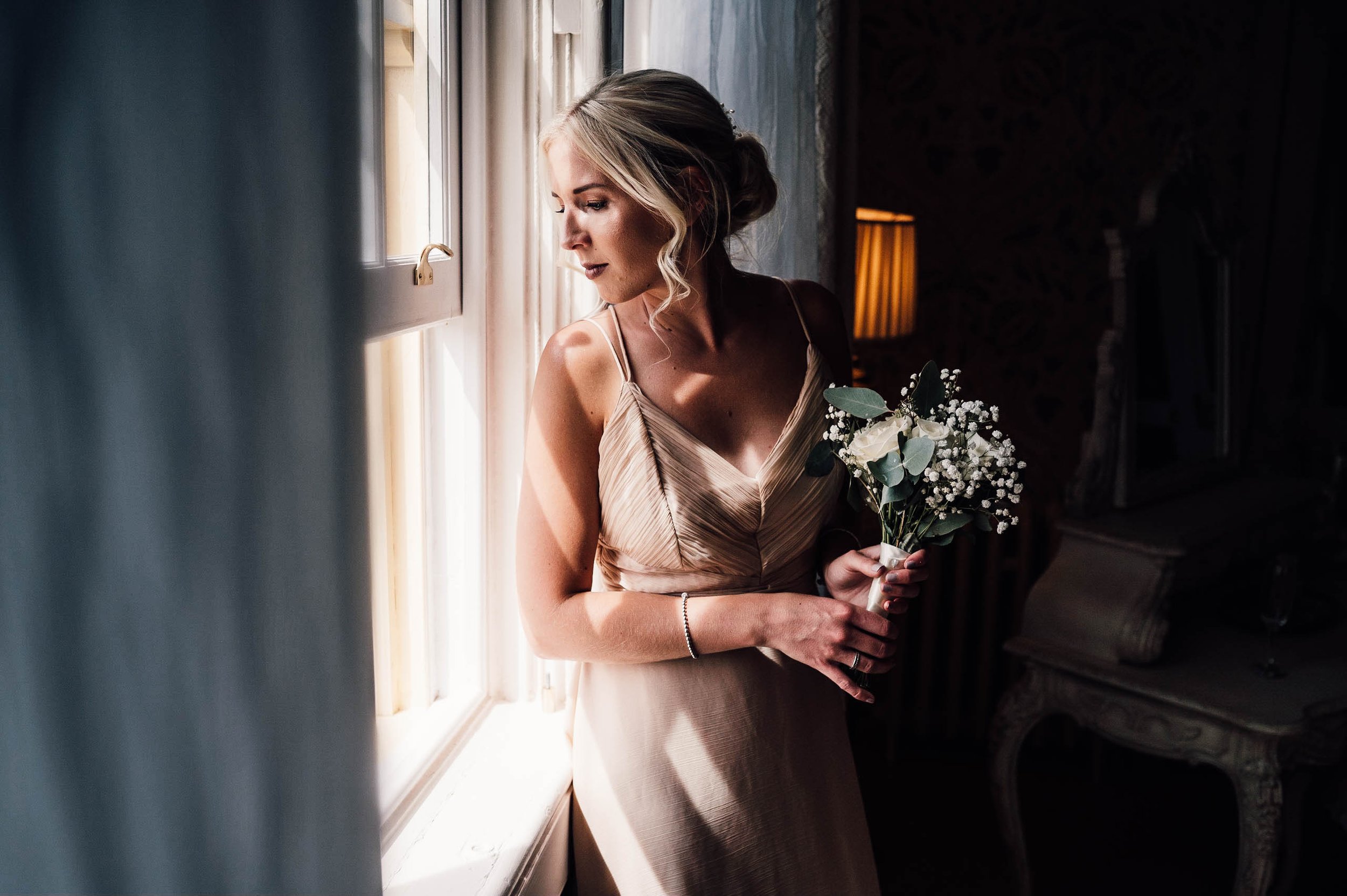 Bridesmaid looking out of the window in the bridal suite at Hodsock Priory