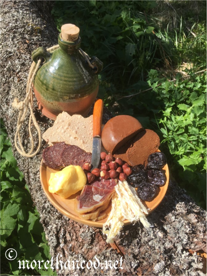 Clockwise from knife: Brown cheese, prunes, stock fish, fenalår (cured leg of mutton), butter, reindeer sausage, flat bread, and hazelnuts (center)