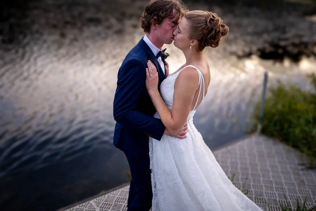 Unscripted moment of groom kissing bride on dock at sunset by Niagara Photographer.jpg
