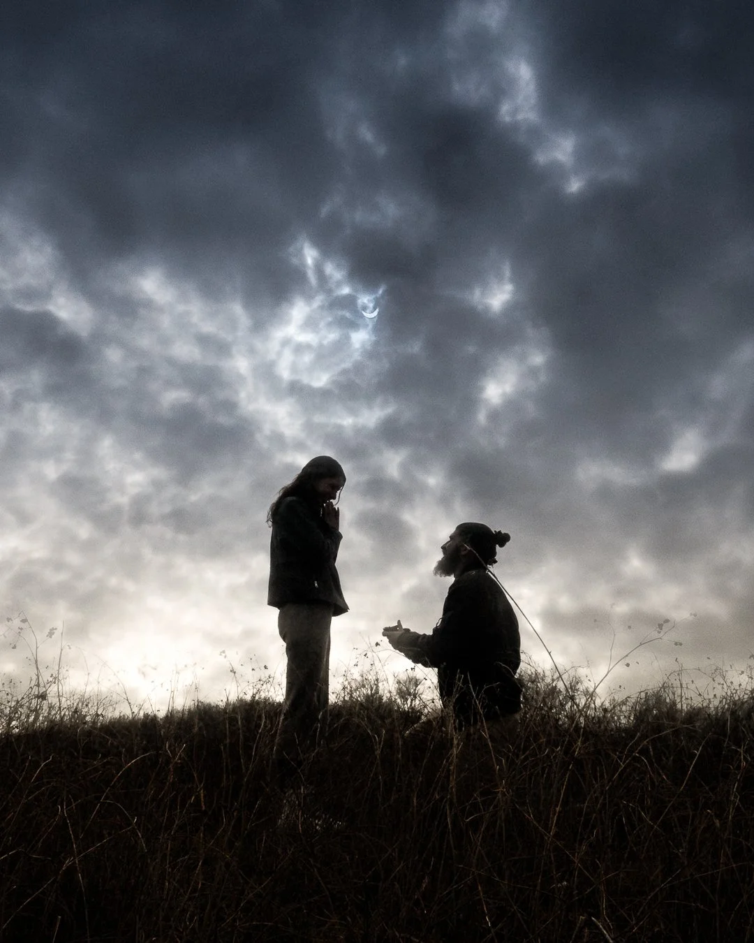 Man surprises girlfriend with a proposal in Niagara. During the Eclipse. He's on one knee on a hill with the sky in the background!