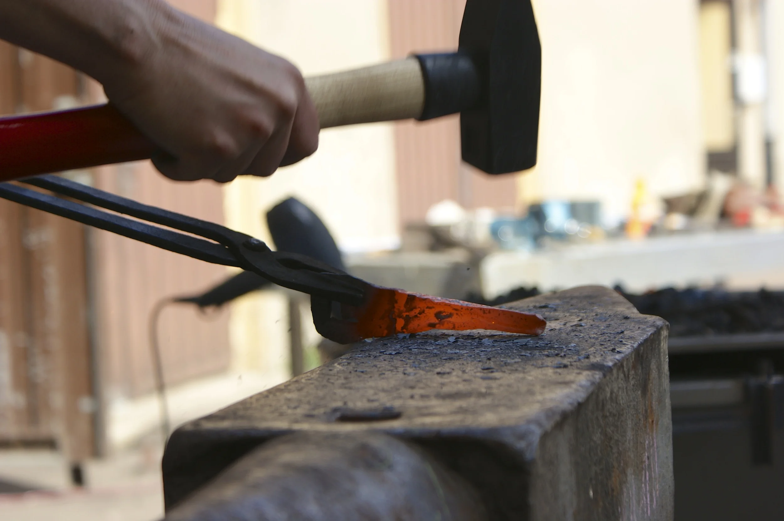 Heather hammering hot iron at the anvil.