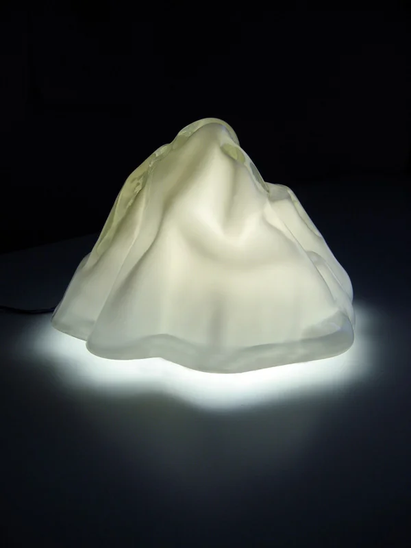   Summit Luminaire   Hand-blown and molded glass, LED's + Acrylic frame 10.5"H × 12" in diameter  Summit exploits the visual deception of scale to provide a new vista for the domestic landscape. The iconic form of a mountain peak is scaled down to fi
