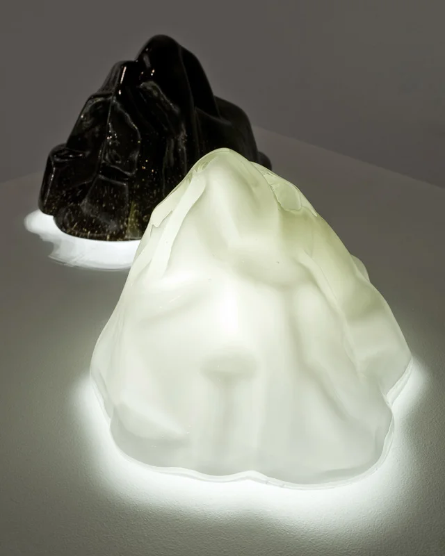   Summit Luminaire   Hand-blown and molded glass, LED's + Acrylic frame 10.5"H × 12" in diameter  Summit exploits the visual deception of scale to provide a new vista for the domestic landscape. The iconic form of a mountain peak is scaled down to fi