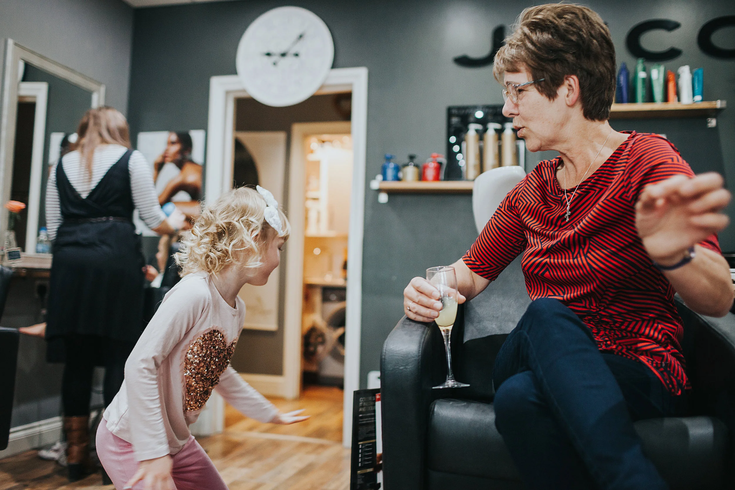  Mother of the bride drinks bucks fizz while keeping an eye on the kids at a hair salon in Marple, Greater Manchester 