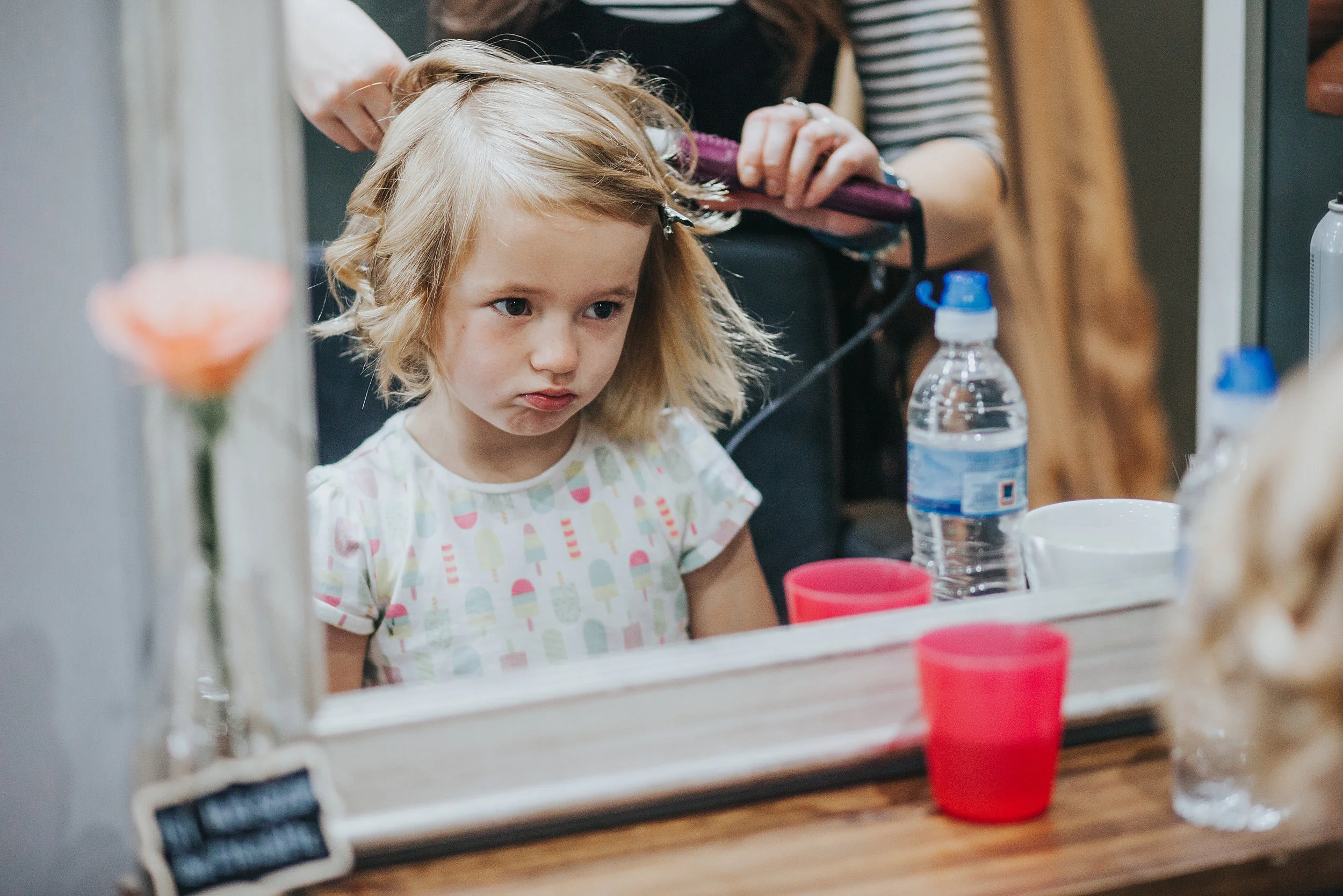 Grumpy cute child gets hair done, while looking very grumpy