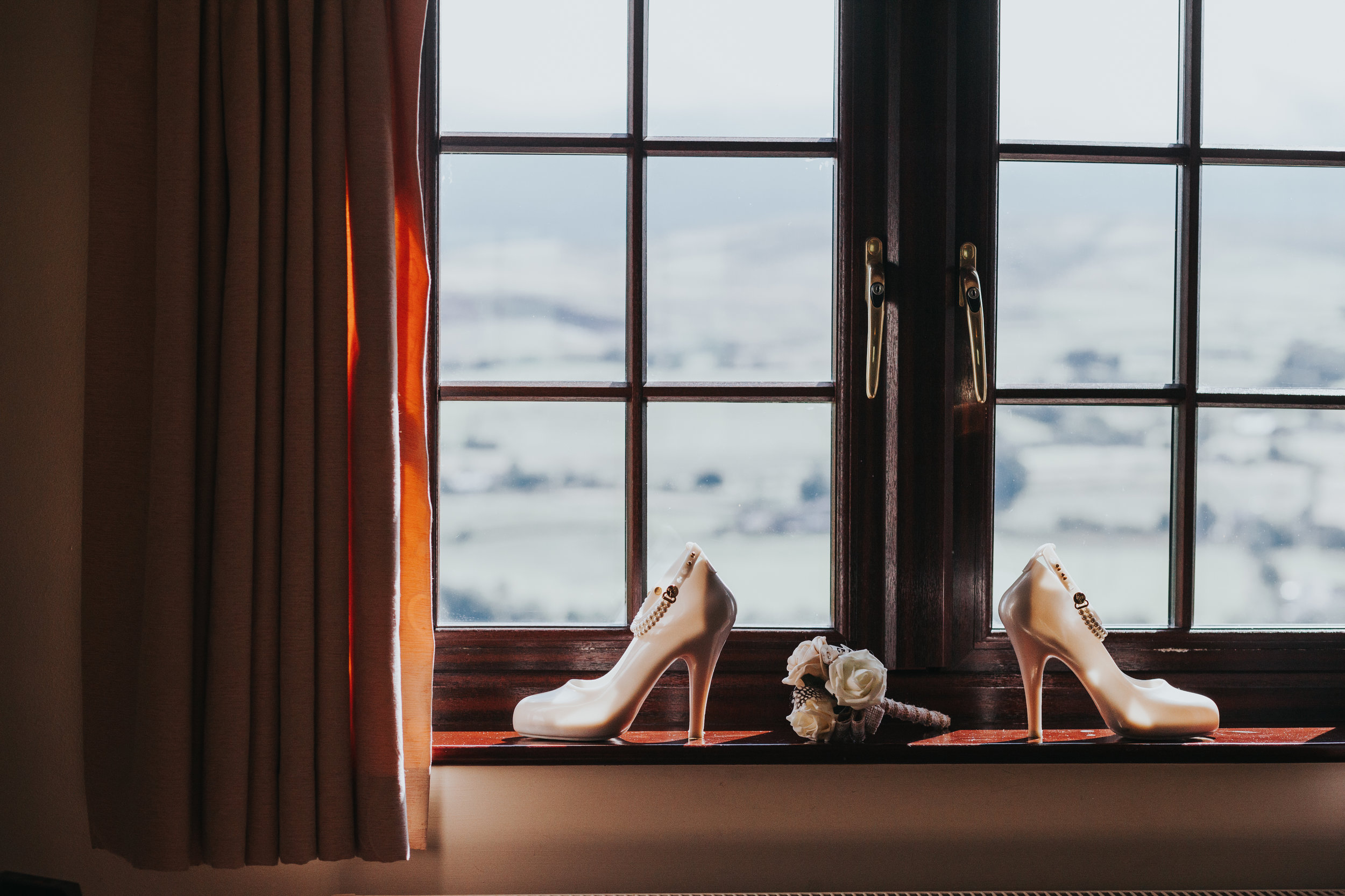  Brides jelly heeled shoes in hotel window, the light coming through them makes them light up like glass slippers, accompanied by chipper child's hand made paper flowers. (Chipper child didn't make them, a professional did) 