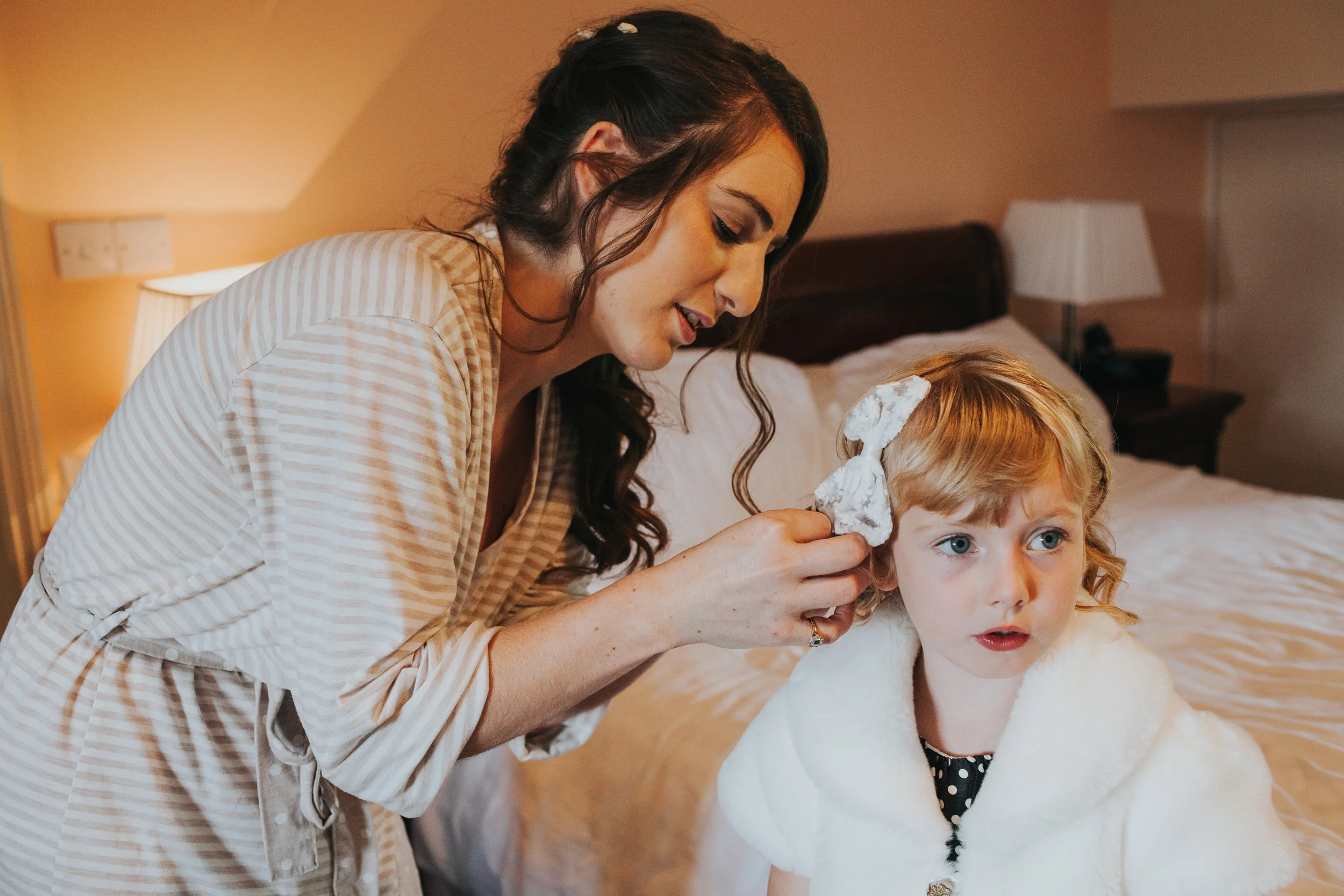 Bride helps chipper child with hair, chipper child looks on pensively.&nbsp; 
