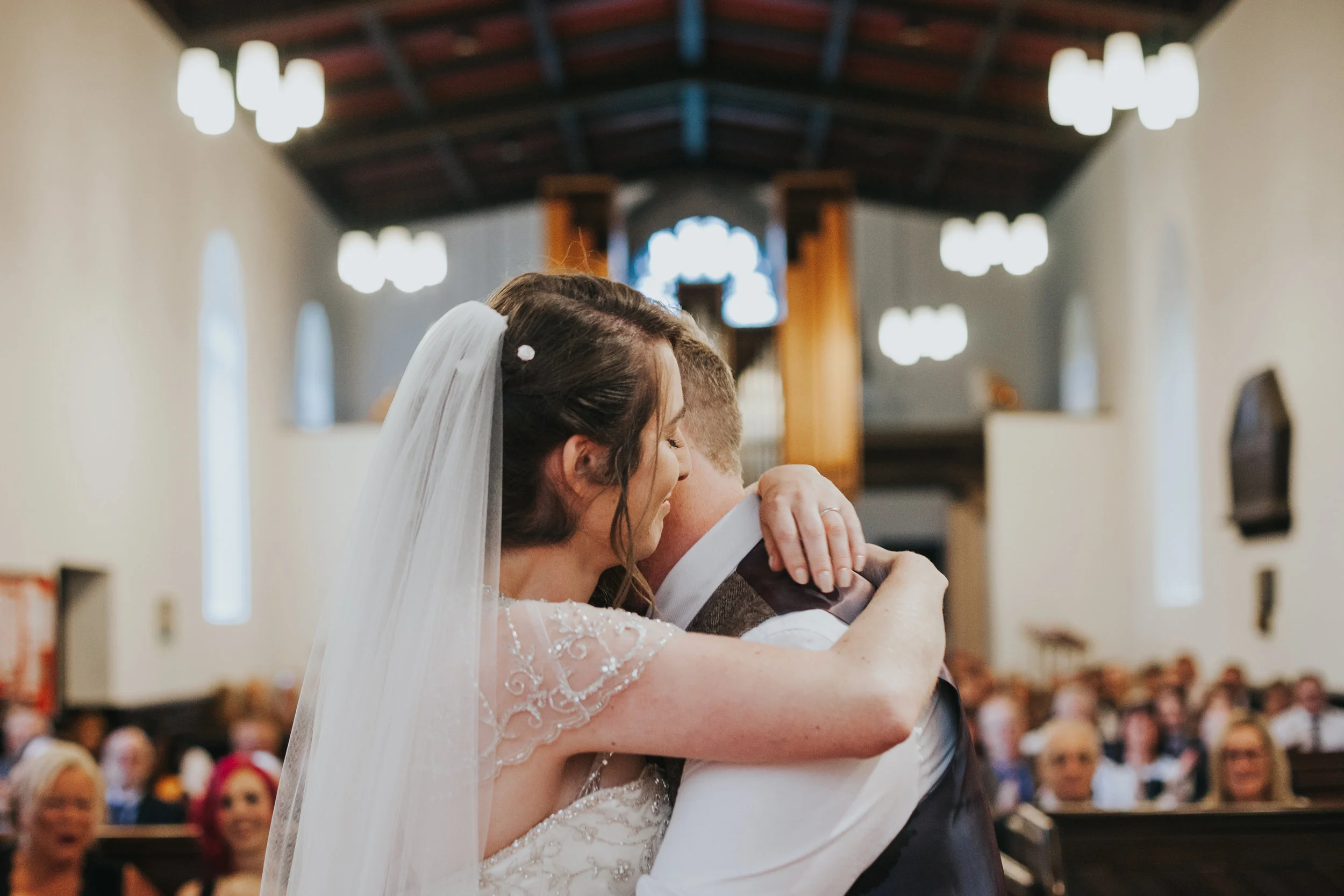 Husband and Wife embrace in church (beautifully captured in a more or less symmetrical shot by photographer)