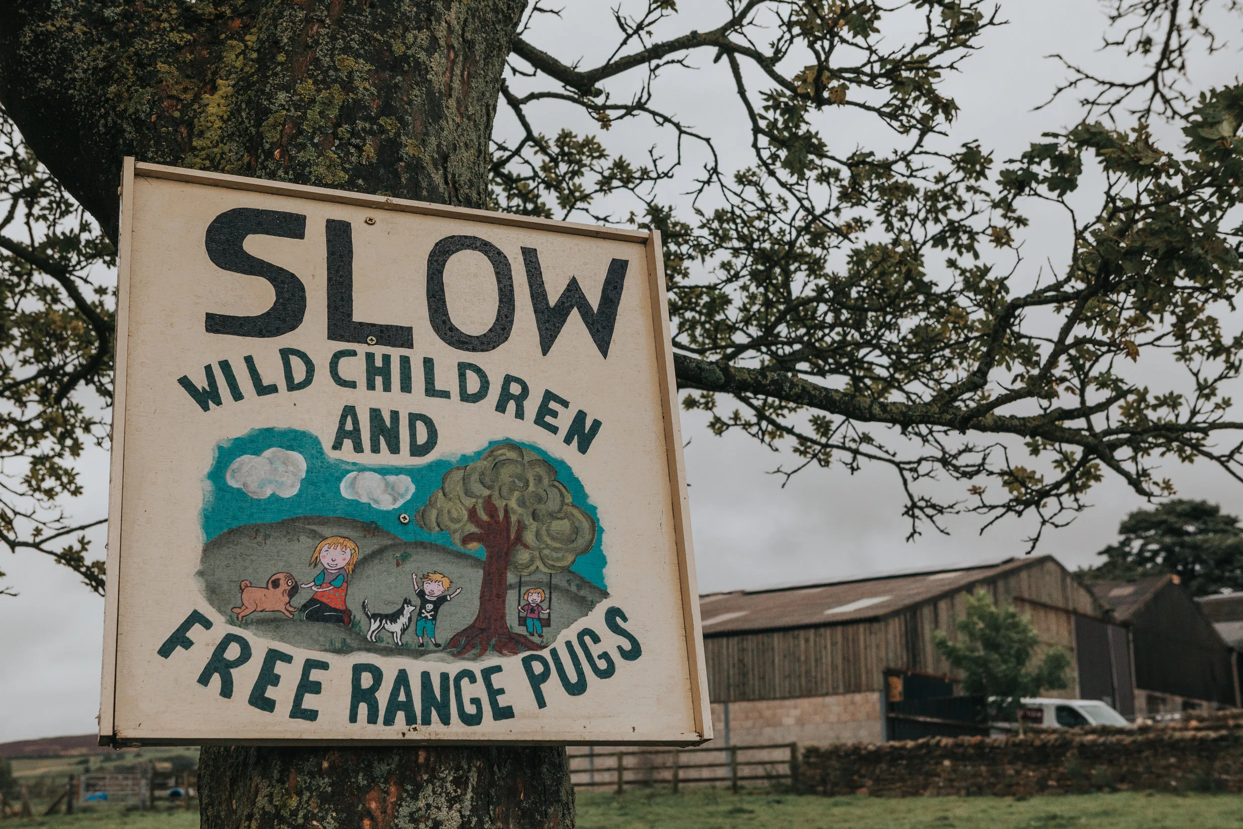 Sign reads "SLOW WILD CHILDREN AND FREE RANGE PUGS" We have arrived at Thornsett Field Farm it seems. 