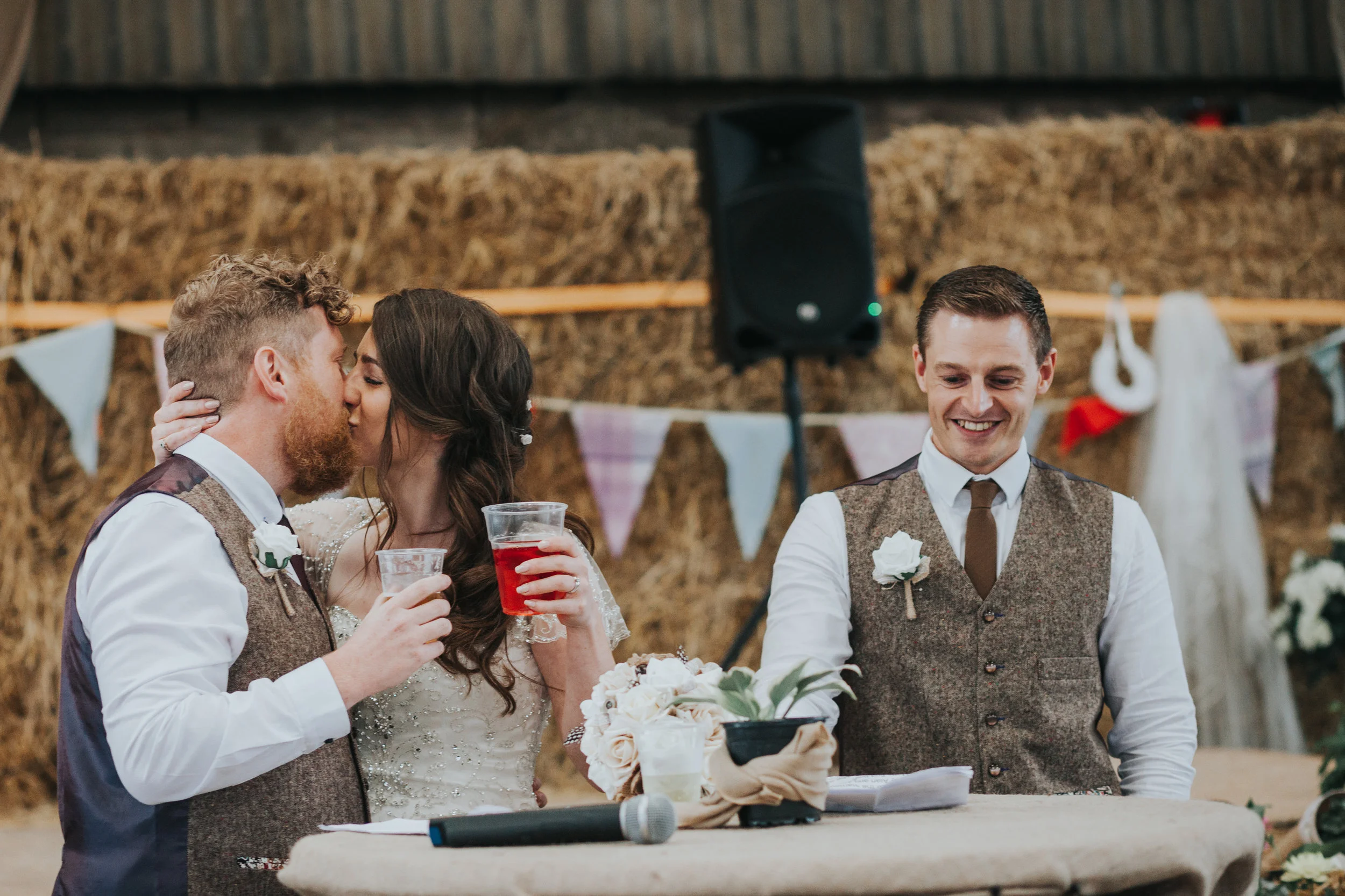 Bride and Groom sneak a cheeky snog while the Best Man laughs. 