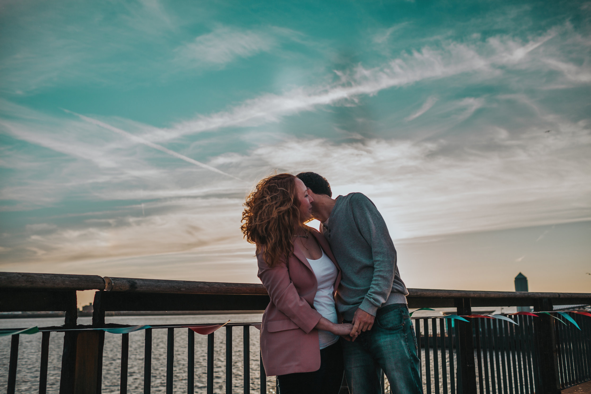 Jess and James with the air plane streaks and teal sky behind them.
