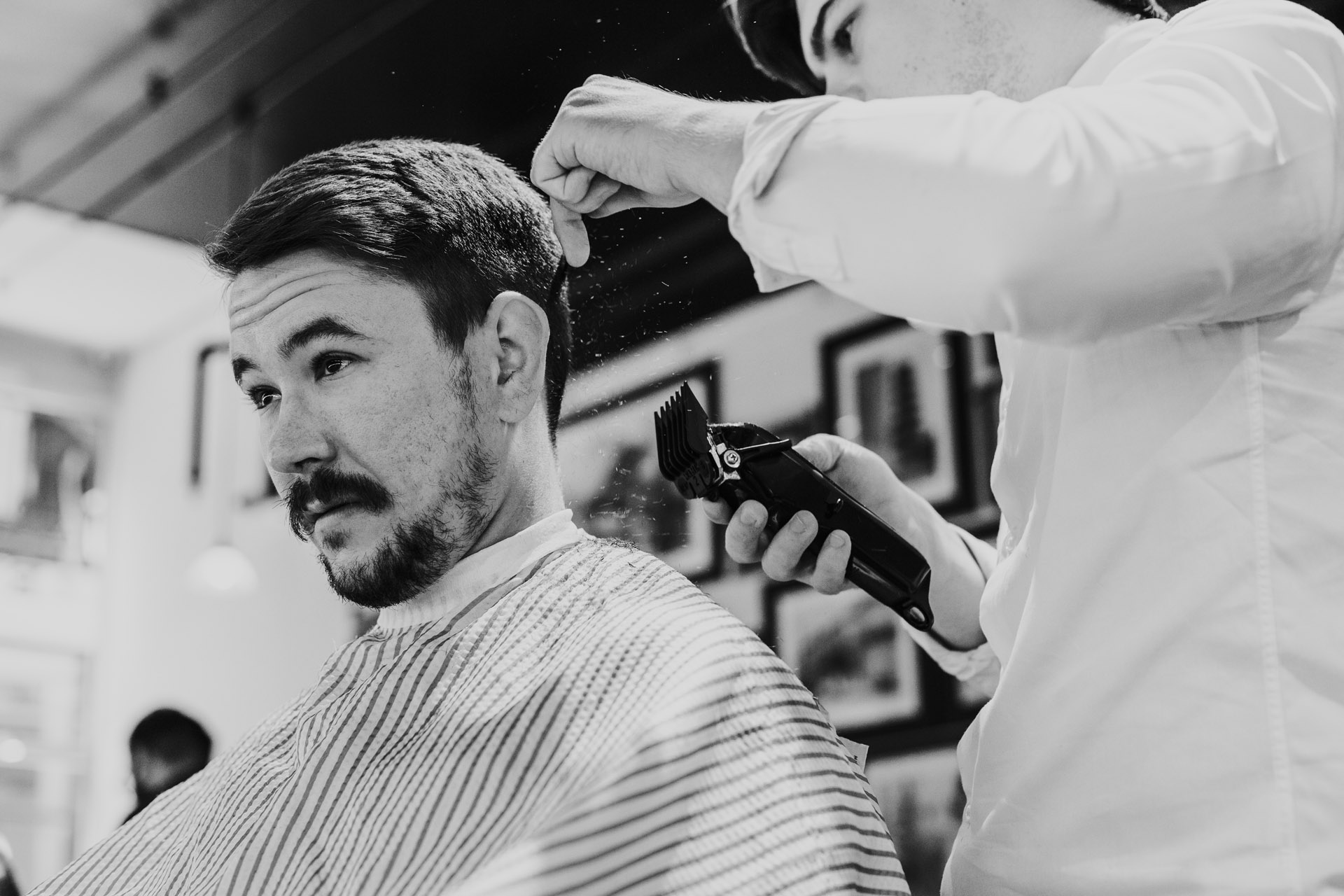 Black and white photograph of groom getting hair shaved.