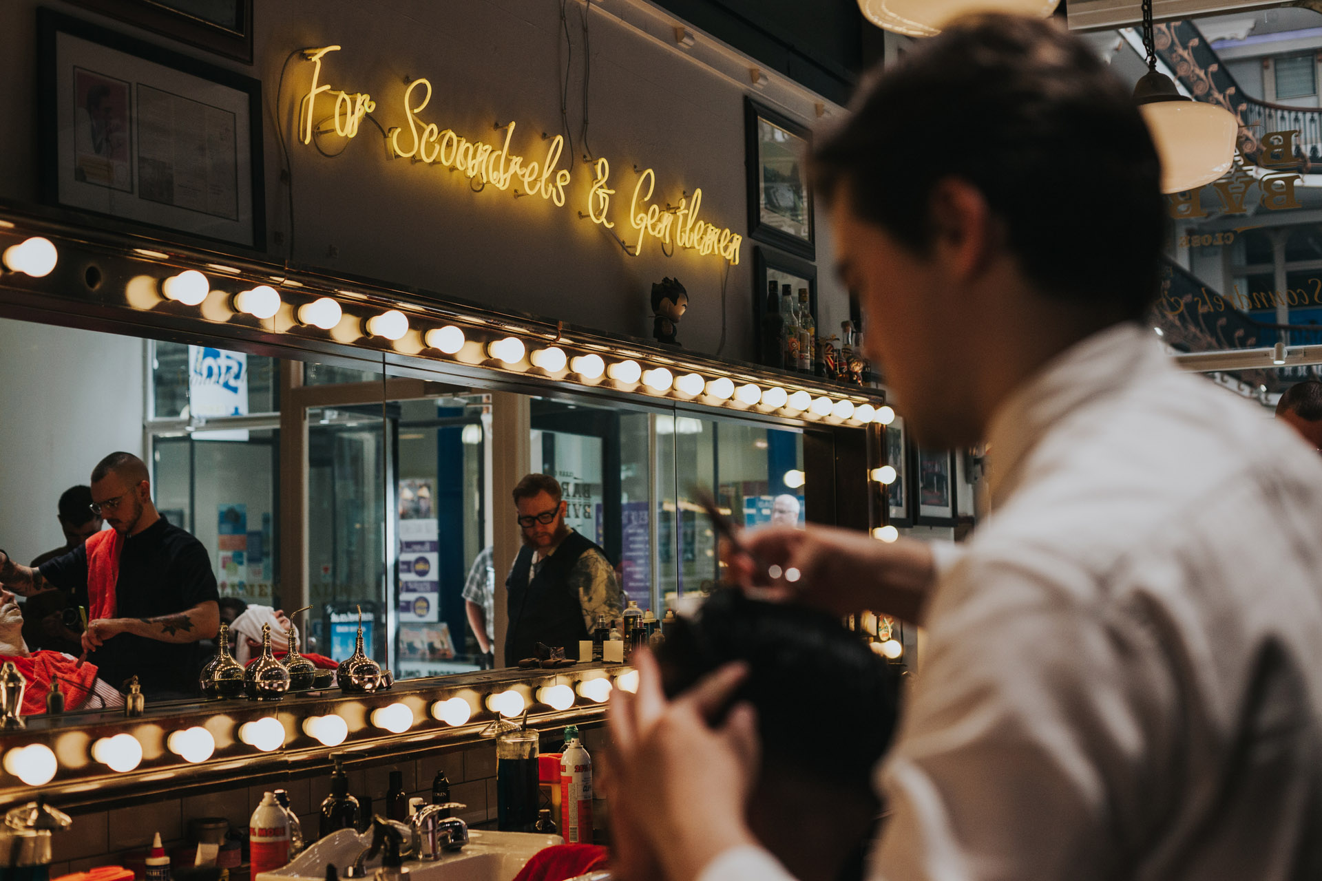 Barber and Groom in forground with neon sign in focus in the back ground