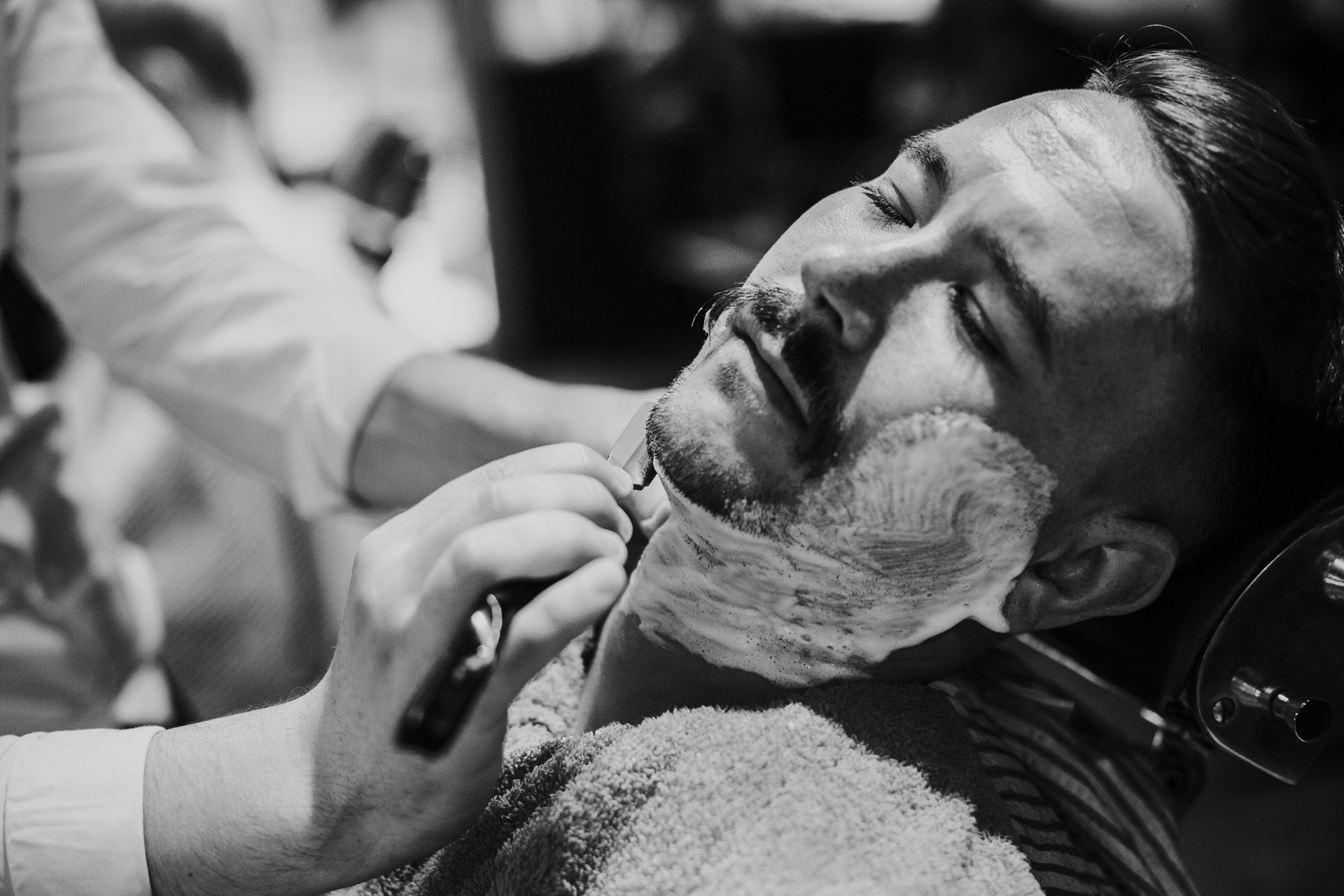 Groom getting cut throat shave, black and white photograph