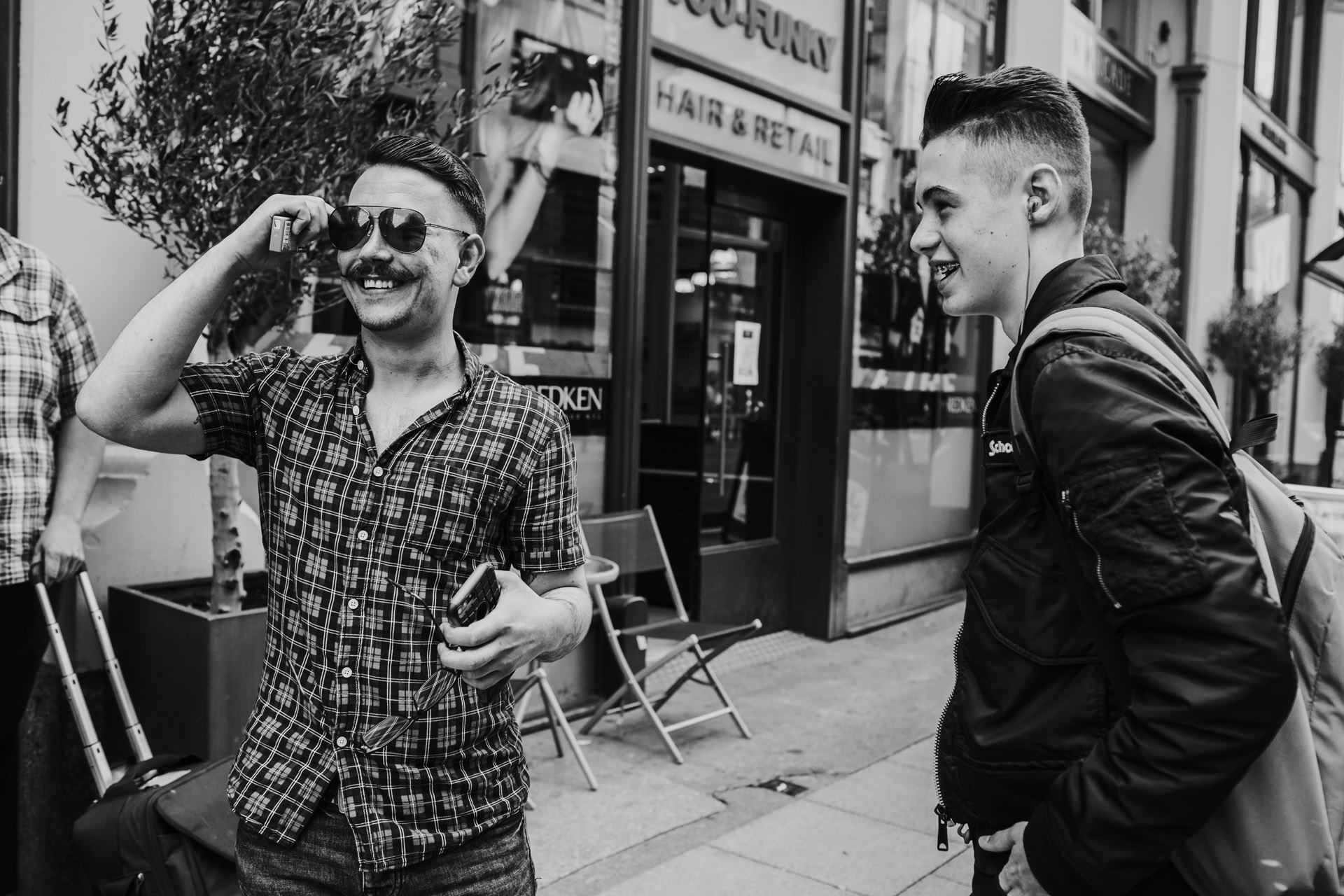 Groom bumps into a friend in the street, image in black and white