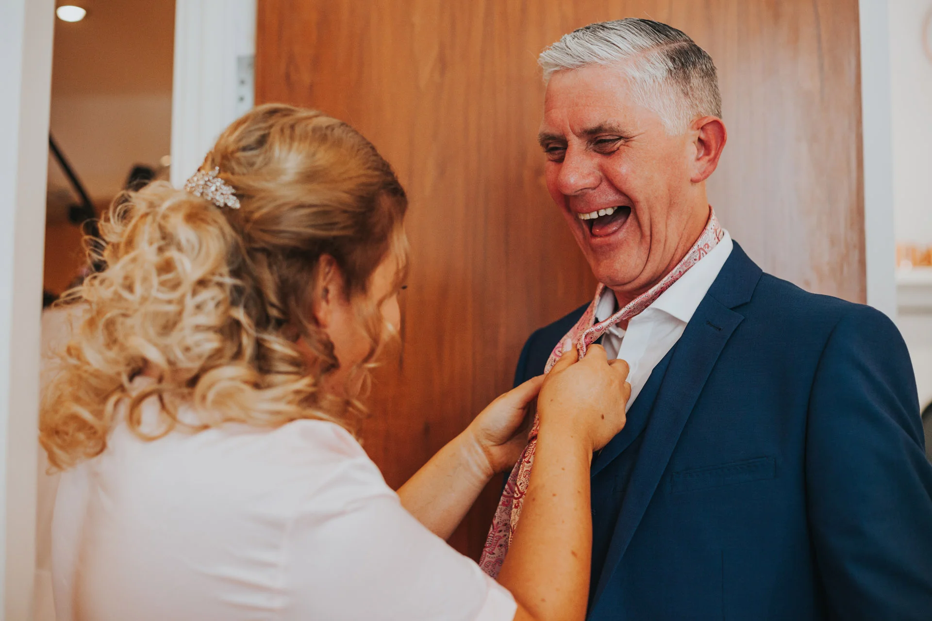 Father of the bride getting his suit fixed and laughing