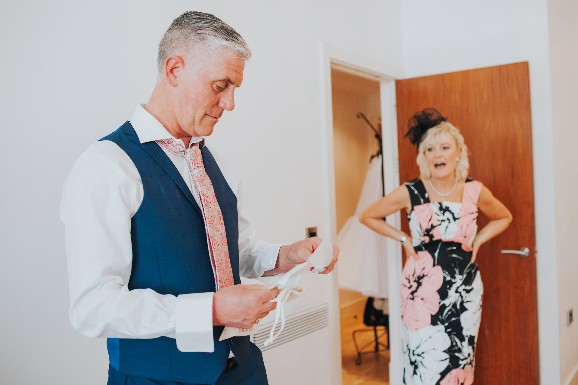 Father of the bride reads a letter from his daughter while to mother of the bride watches him.