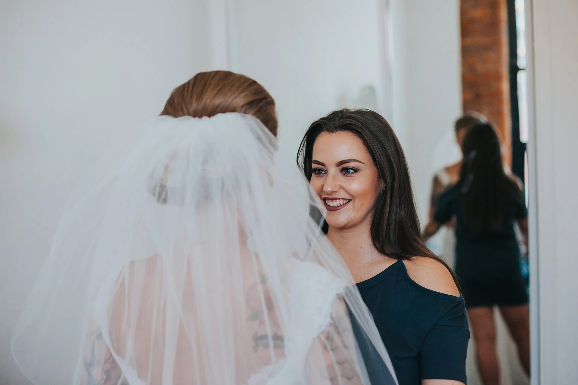 Bridesmaid looks at Bride smiling. 