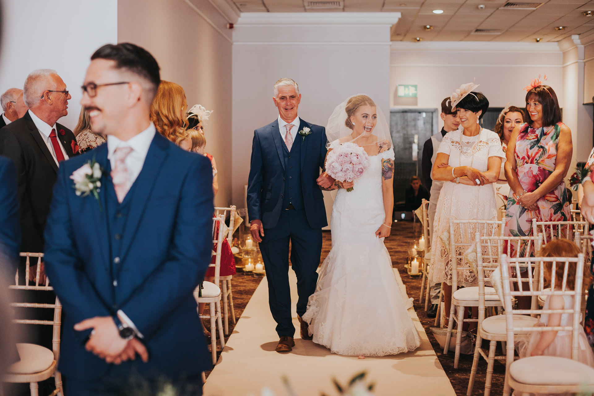 Bride walks down the aisle with her father looking excited. 
