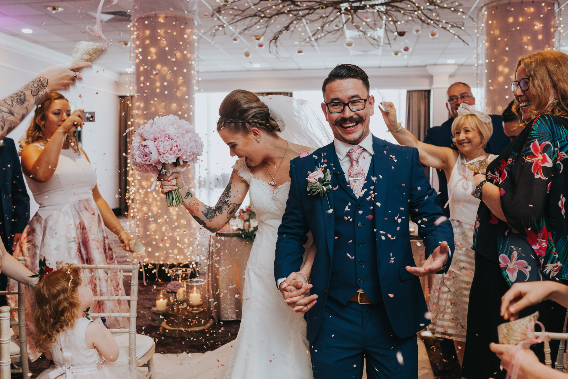 Guests throw confetti as bride and groom walk down the aisle. 