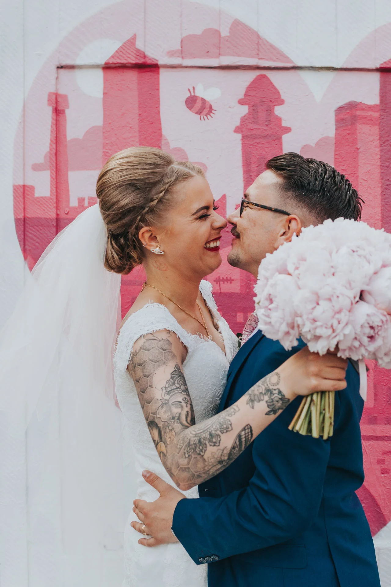Bride and Groom stand in front of heart shaped street art showing the Manchester Skyline, Northern Quarter.