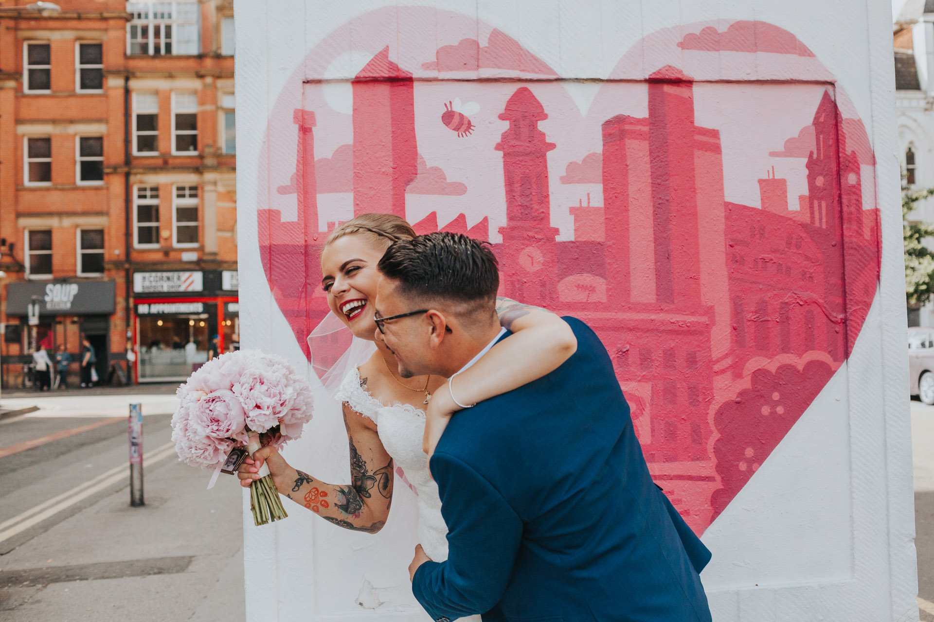 Couple laugh together in front of Manchester Graffiti. 