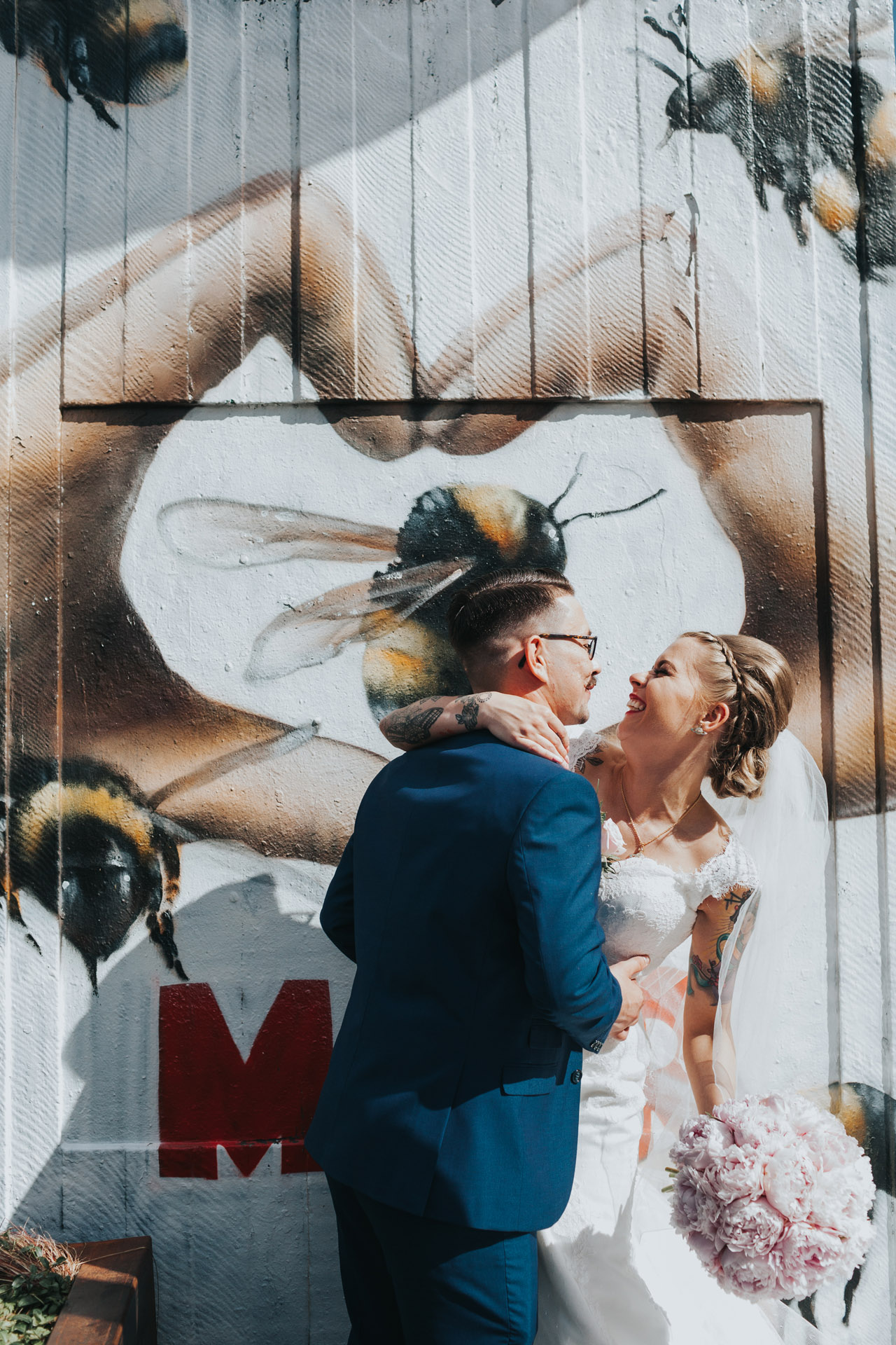 Bride and Groom pose in front of Manchester Bee Hand Heart Street art in Stevenson Square, The Northern Quarter, Manchester. 