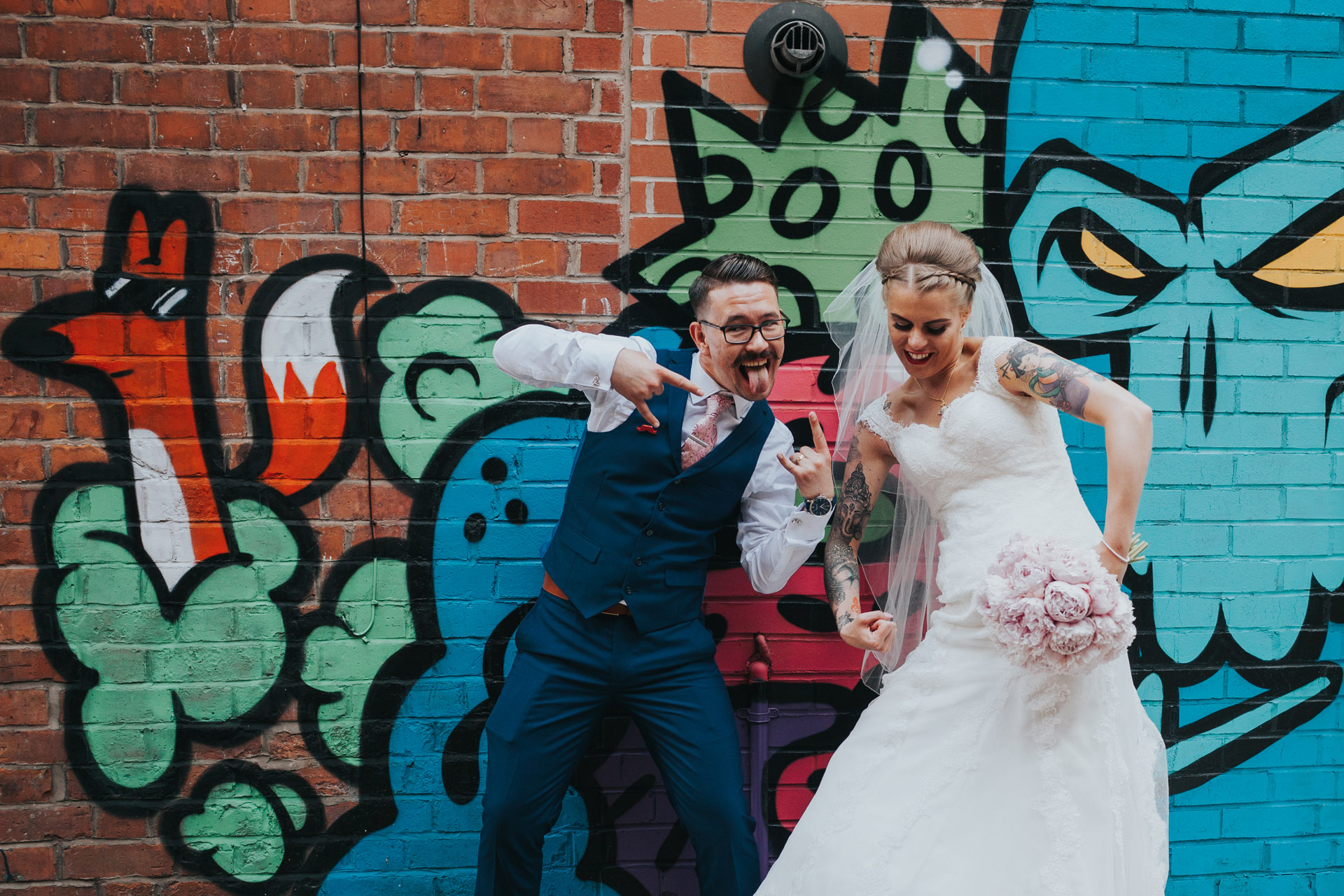 Bride and Groom pose in front of street art behind The Peer Hat, Manchester, Northern Quarter. 