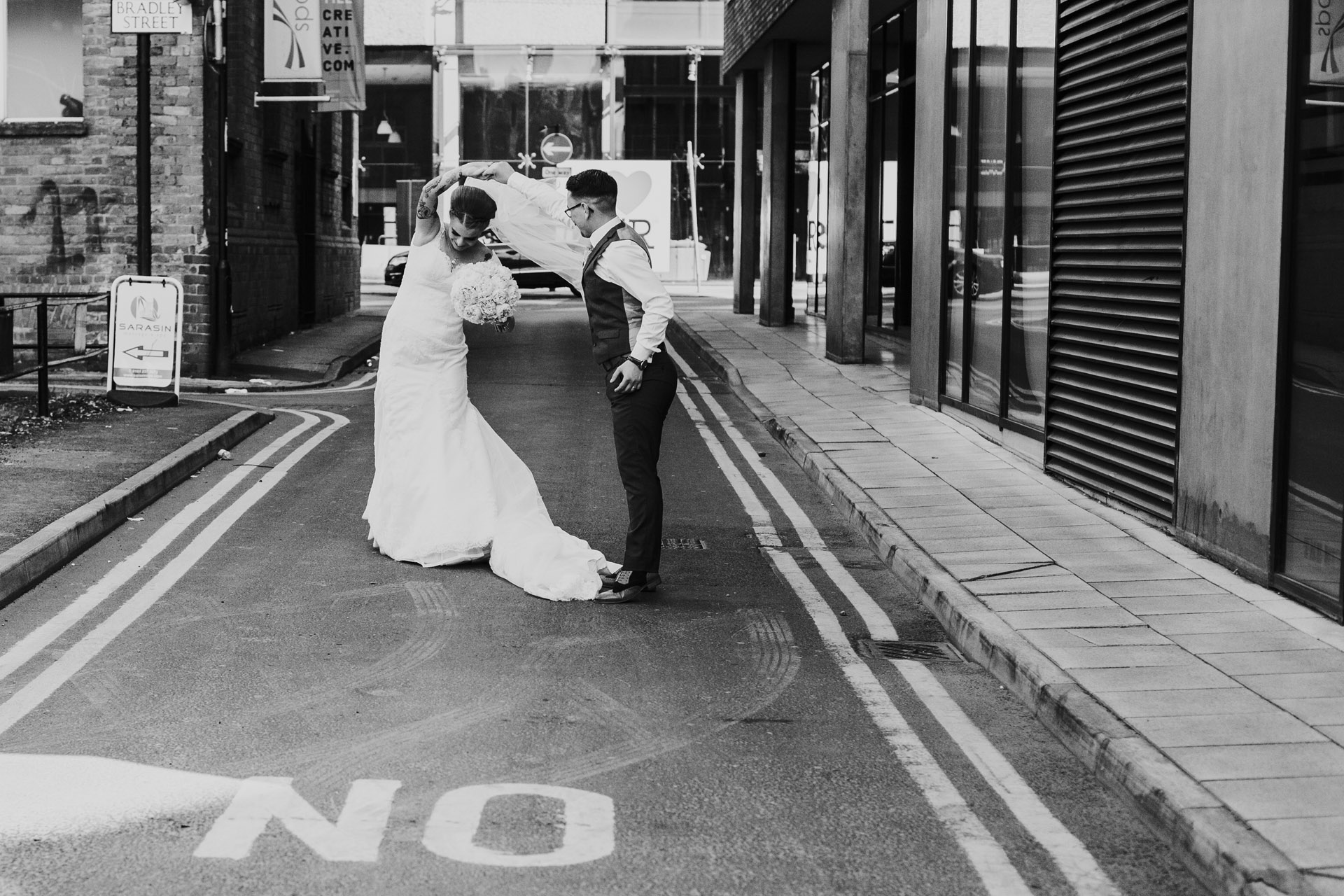 Black and white photograph of couple dance in Manchester back alley on their wedding day. 