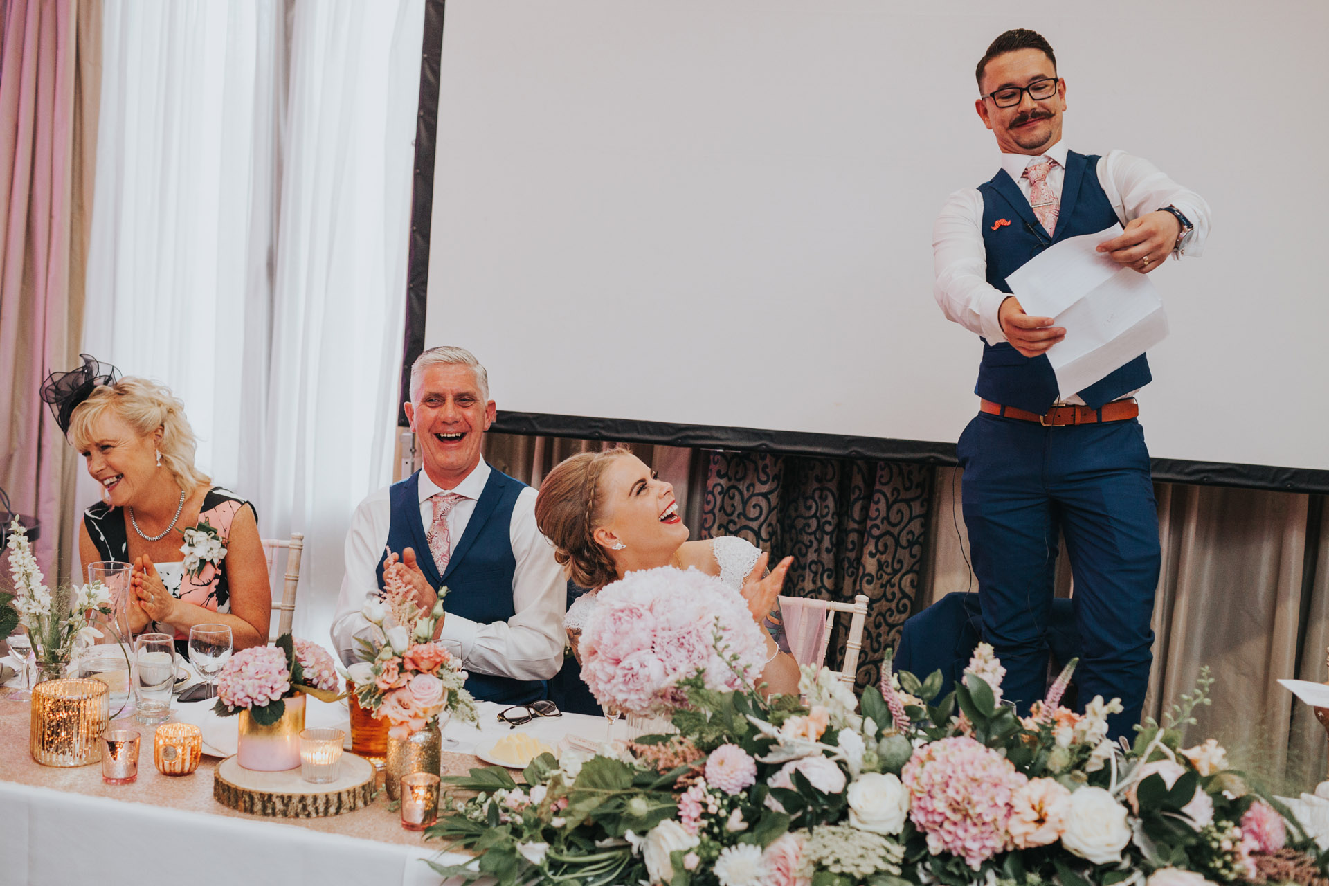 Groom standing on chair to make speech. 