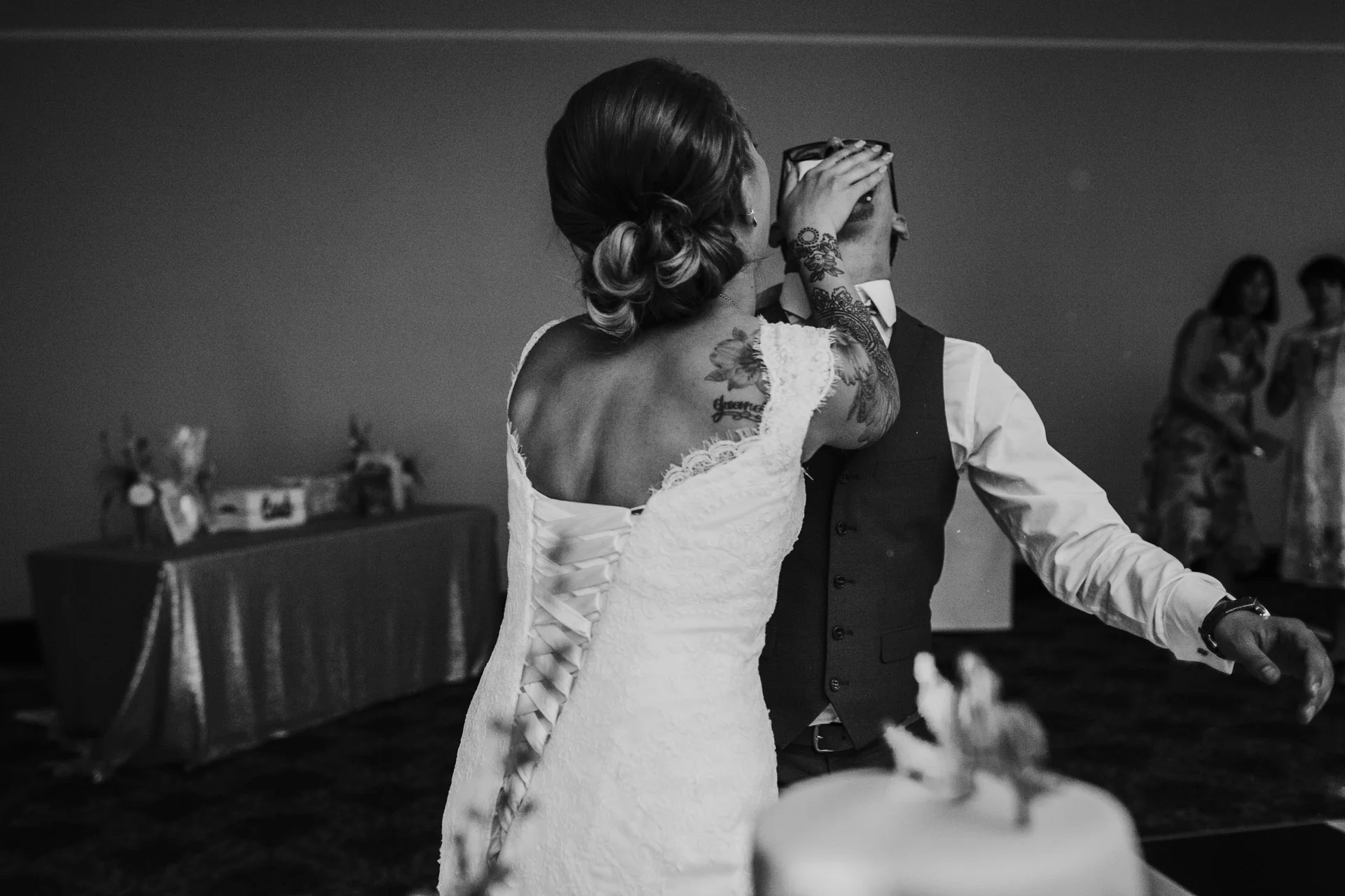 Bride feeds cake to groom. Image in black and white. 