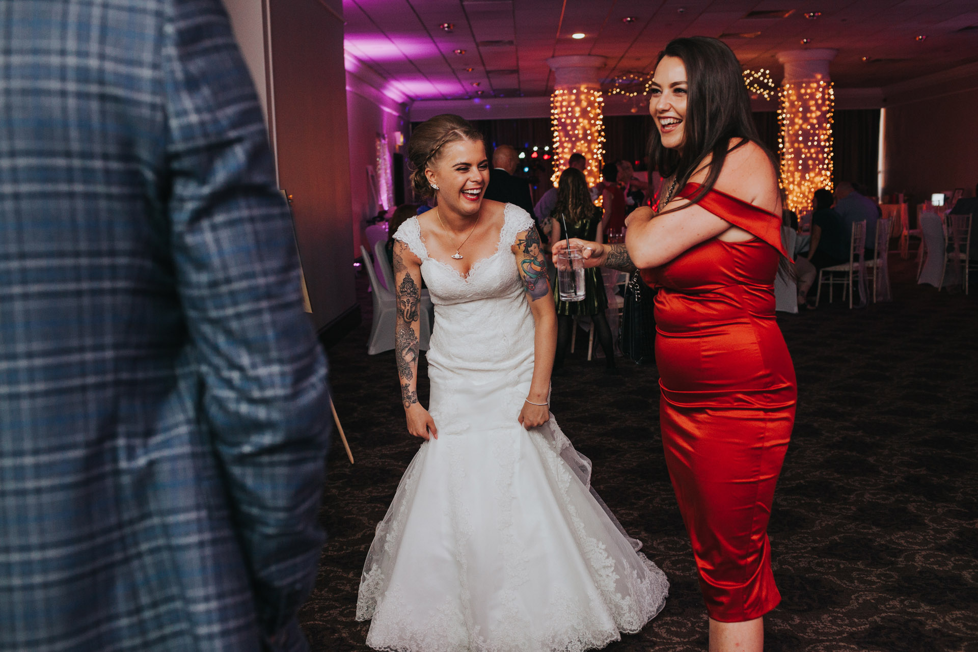 Bride laughing with friends on dance floor. 