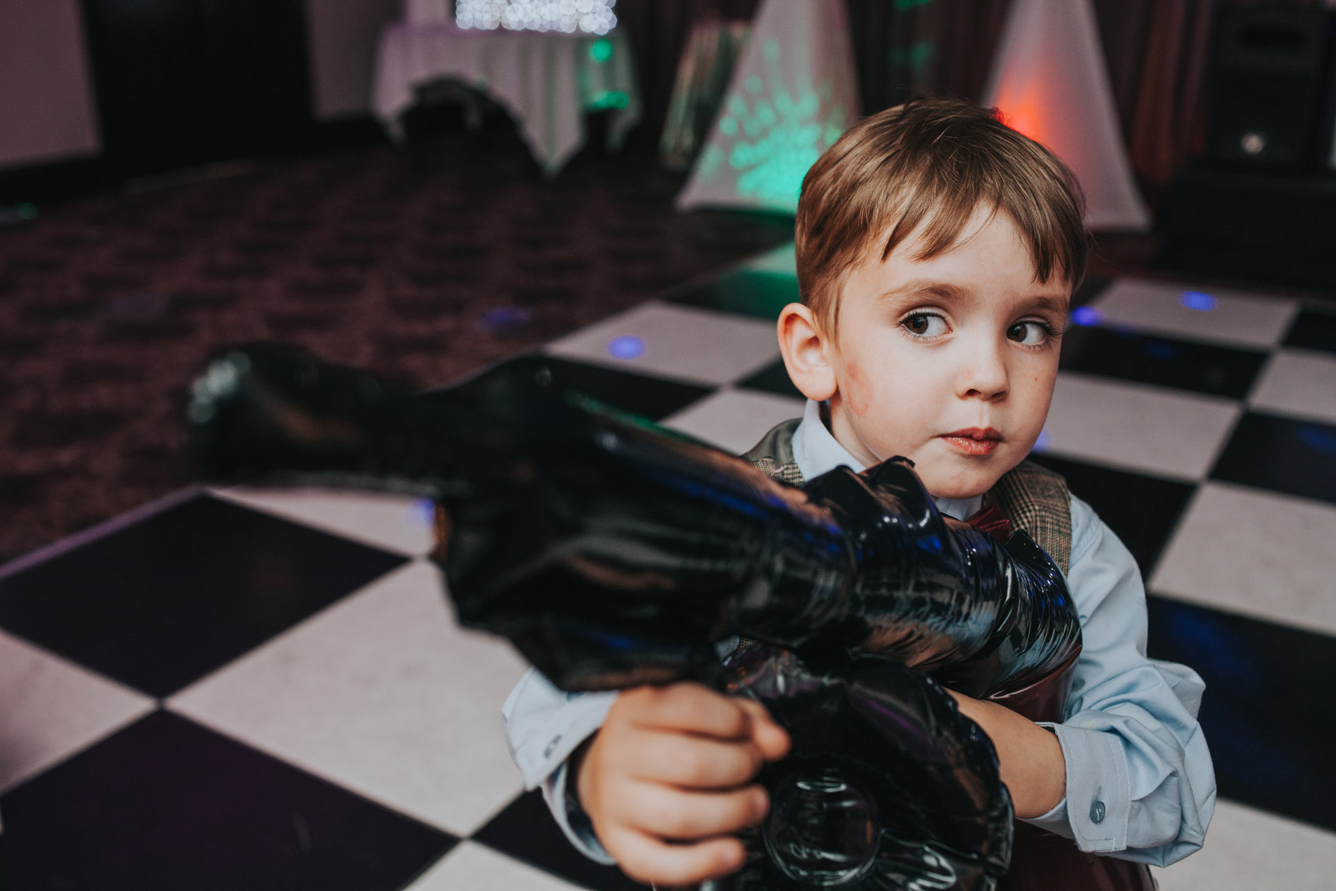 Child holding blow up machine gun at Manchester wedding party.