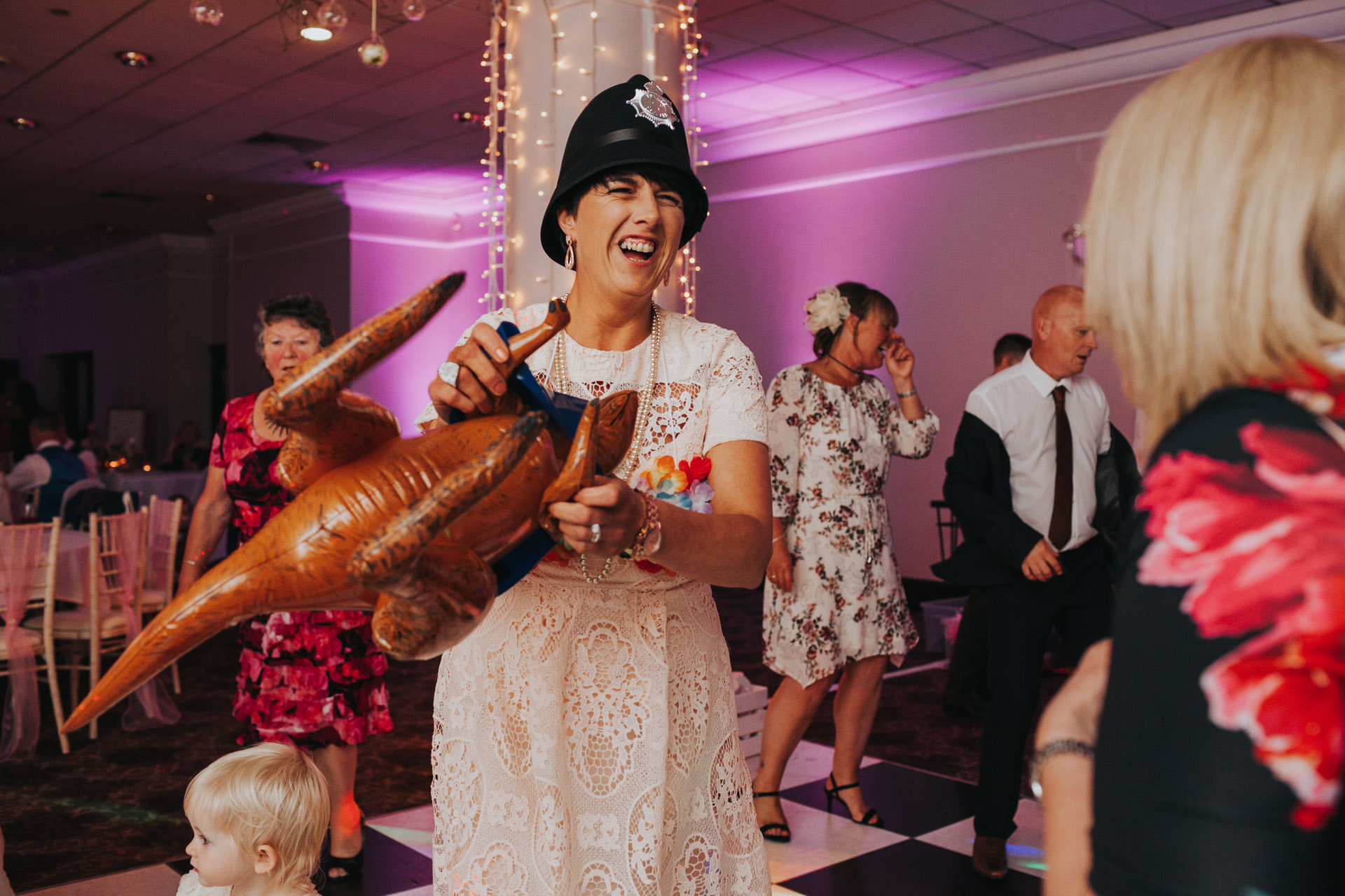 Wedding guest wearing a police helmet and holding a blow up dinosaur at Manchester Wedding. 