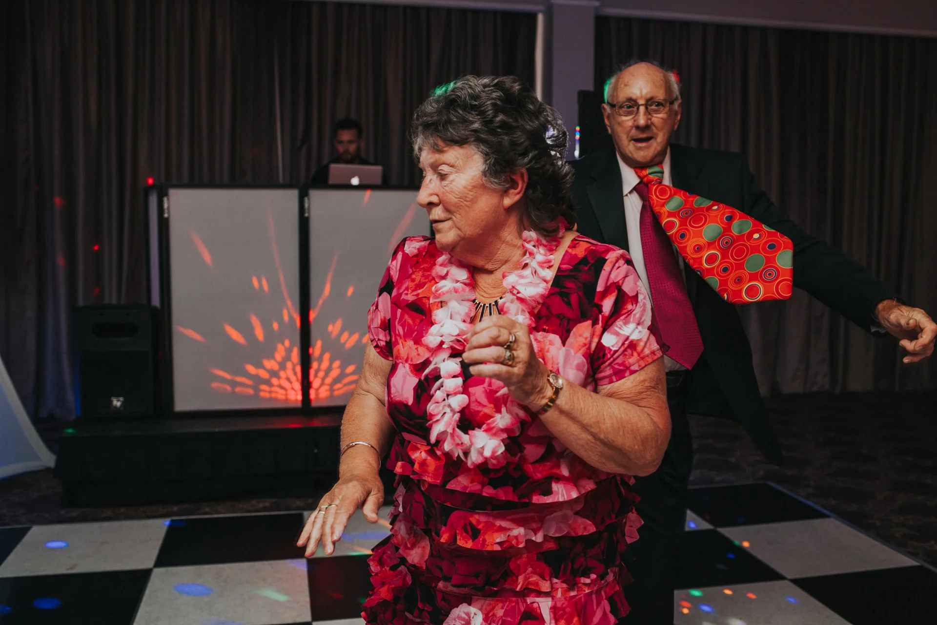 Man with giant tie dances with lady at Manchester Wedding Party. 