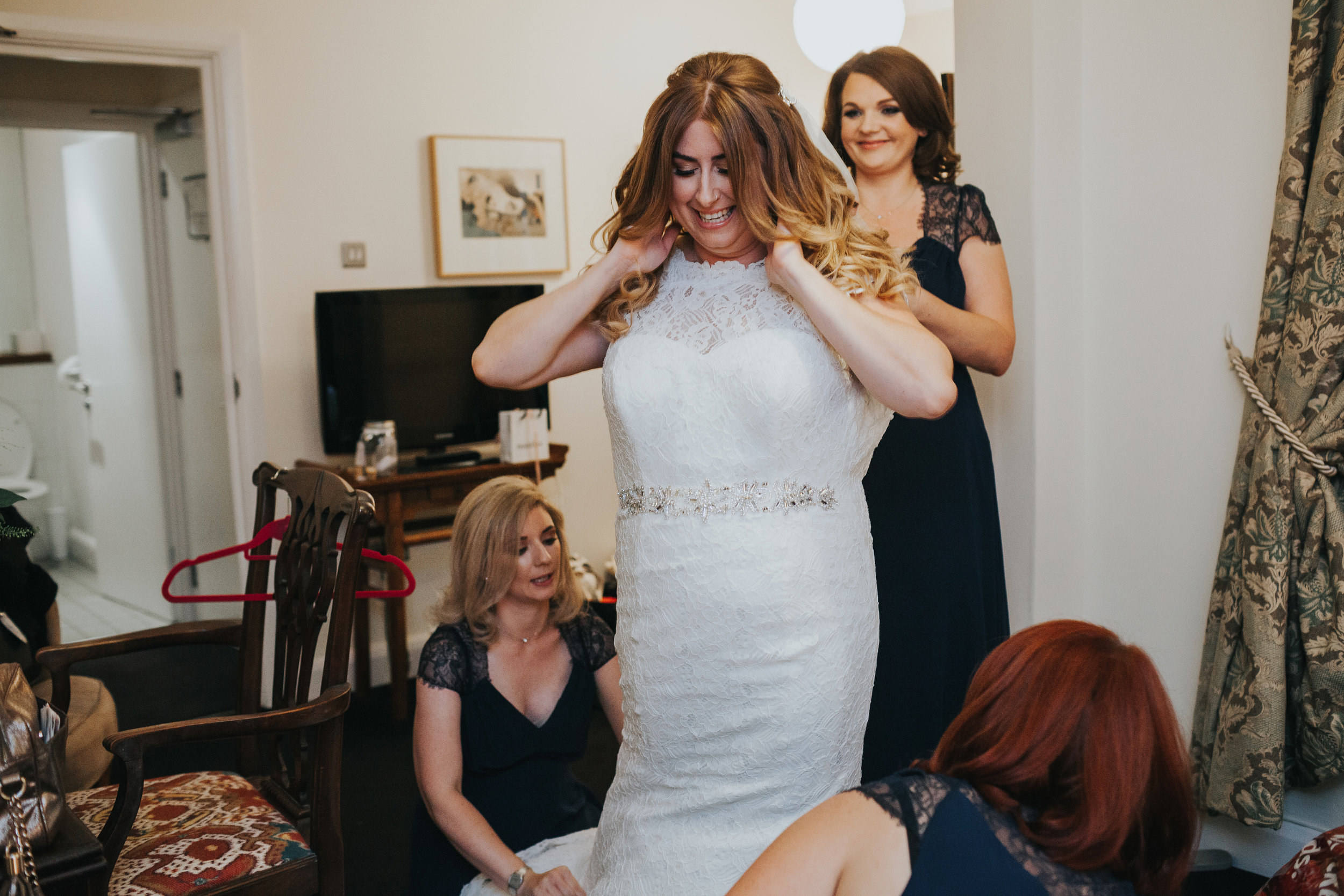 Bride gets into her wedding dress in her hotel room in merseyside. 