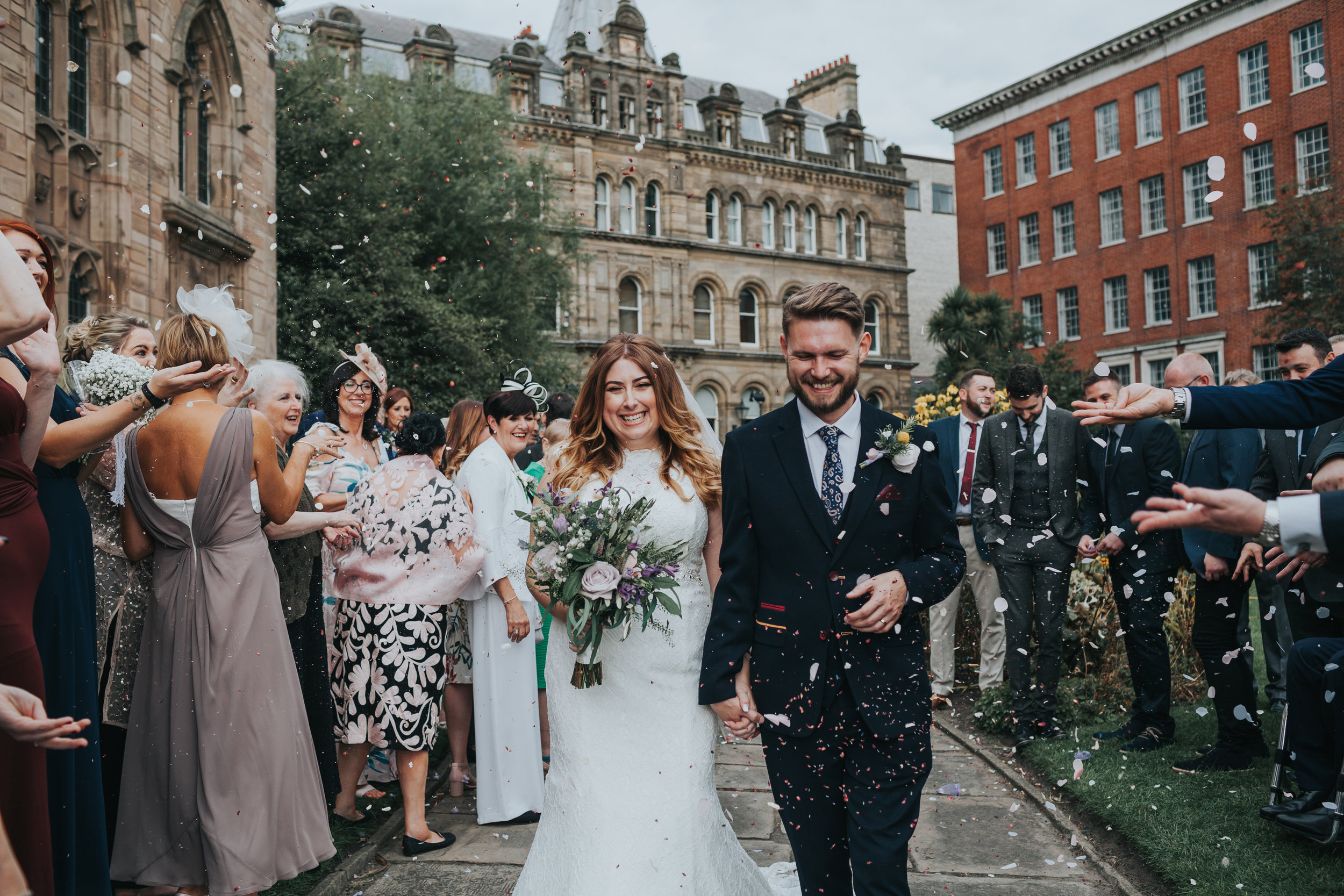 Bride and groom having confetti thrown at them by wedding guests.