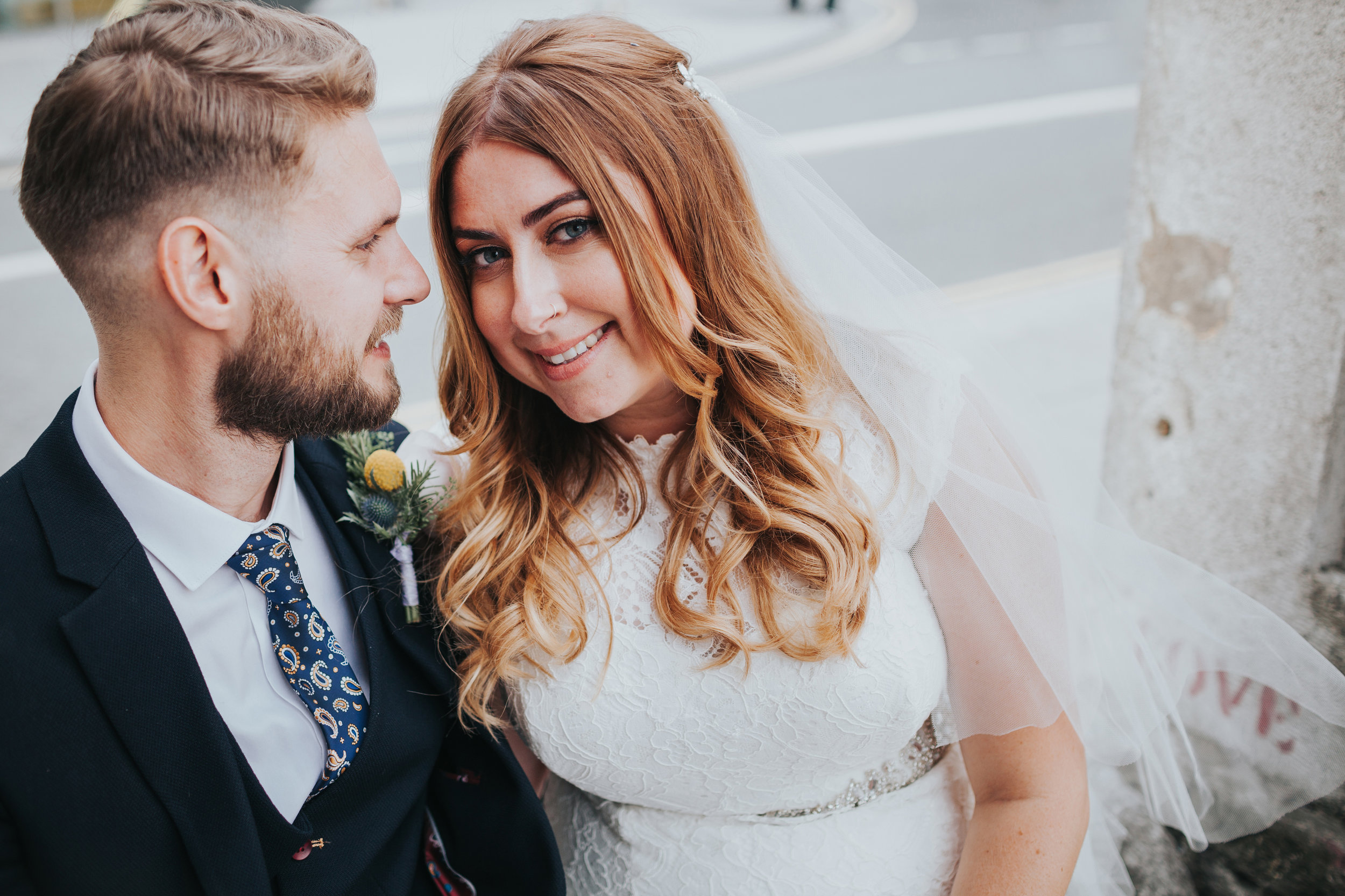 Couples portrait of bride and groom, veil blows in the wind.
