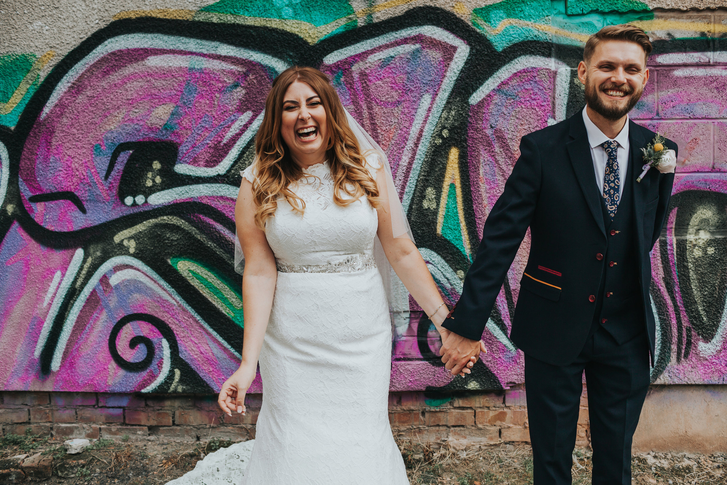 Bride and Groom in front of purple graffiti. 