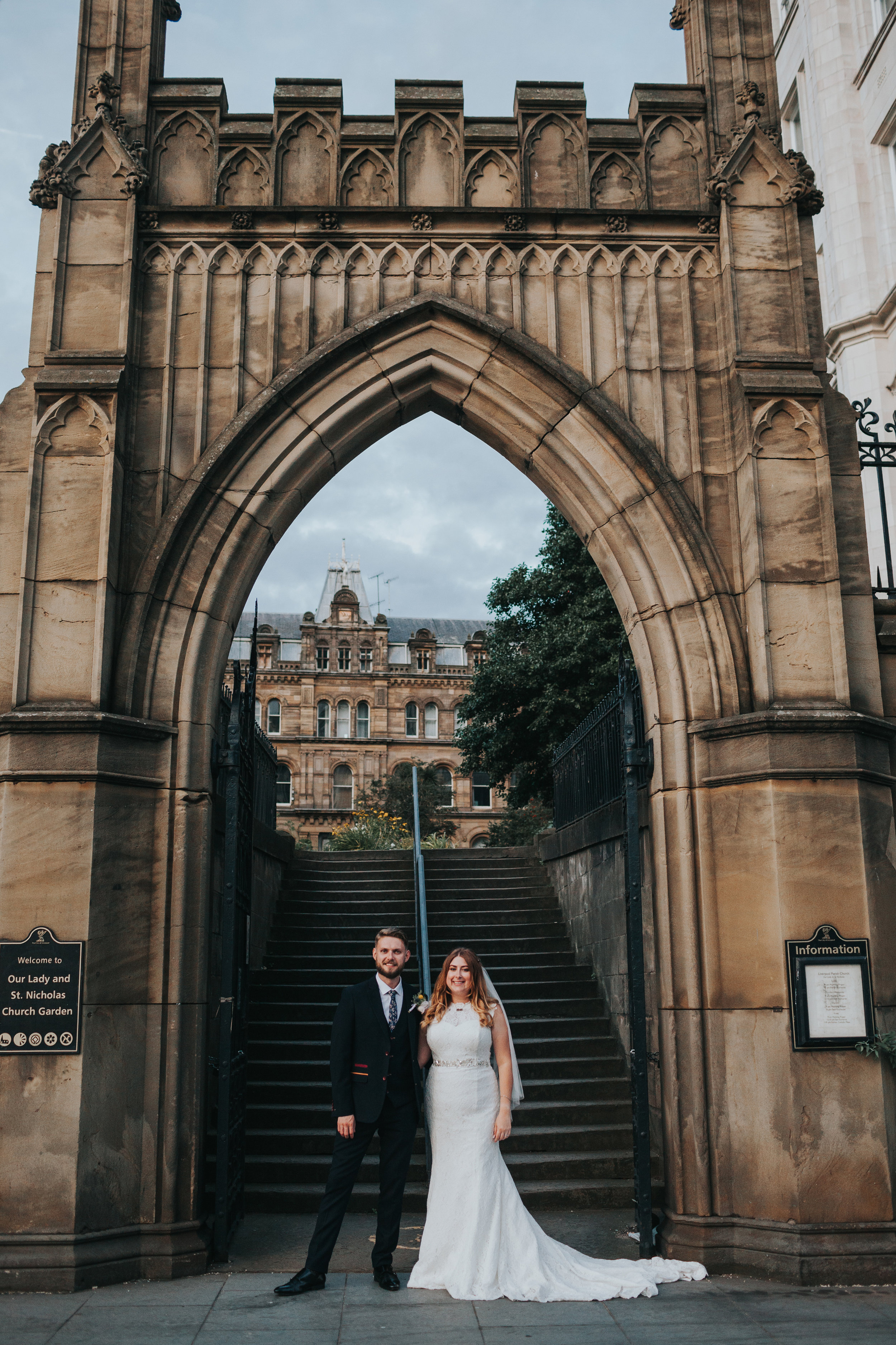 Bride and Groom stand together under grand archway, Liverpool. 