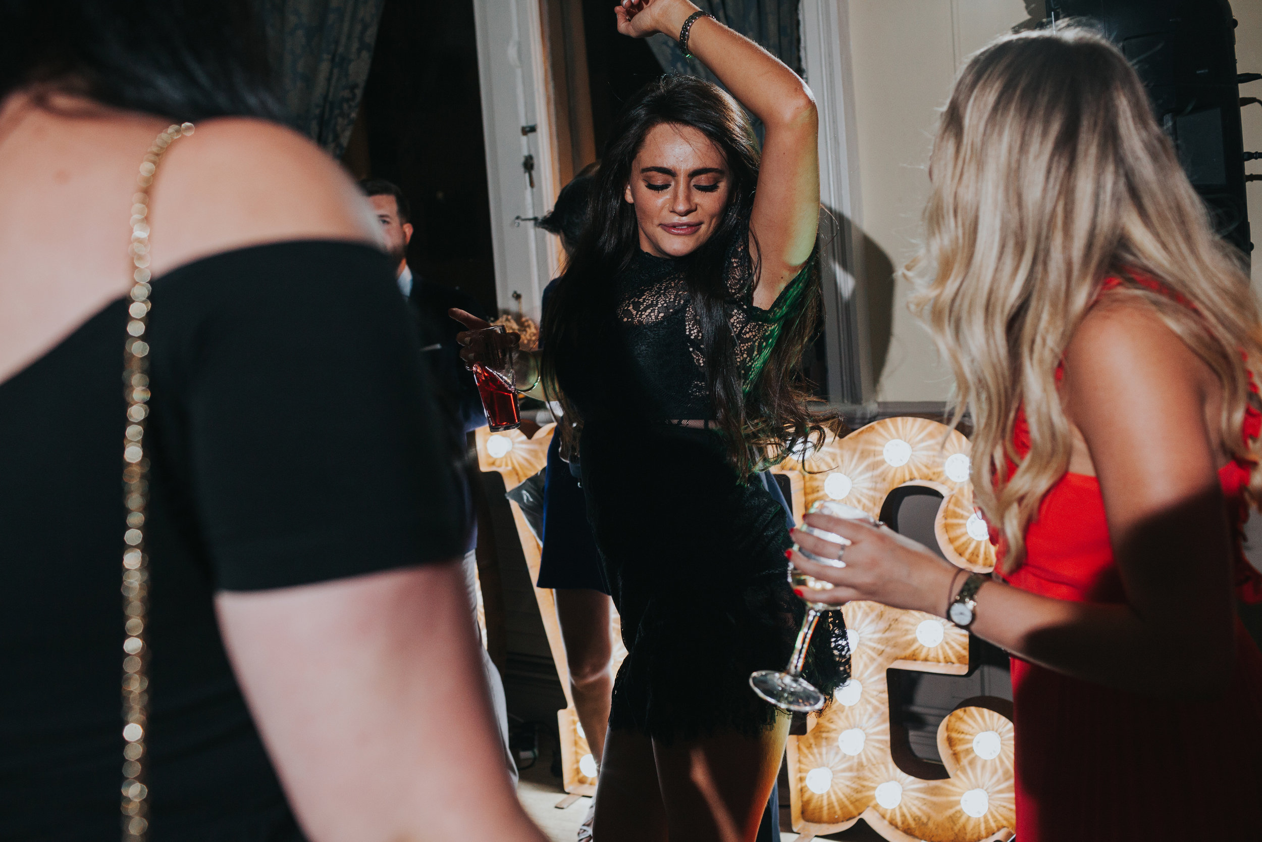 Wedding guest wearing black dress dancing. 