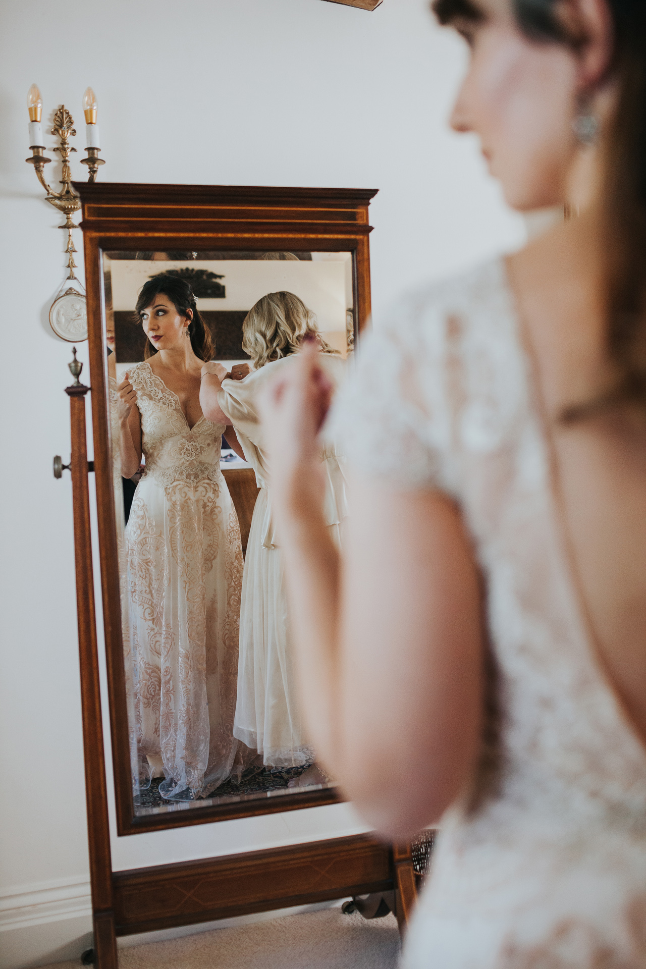 Bride standing in front of the mirror in her wedding dress. 