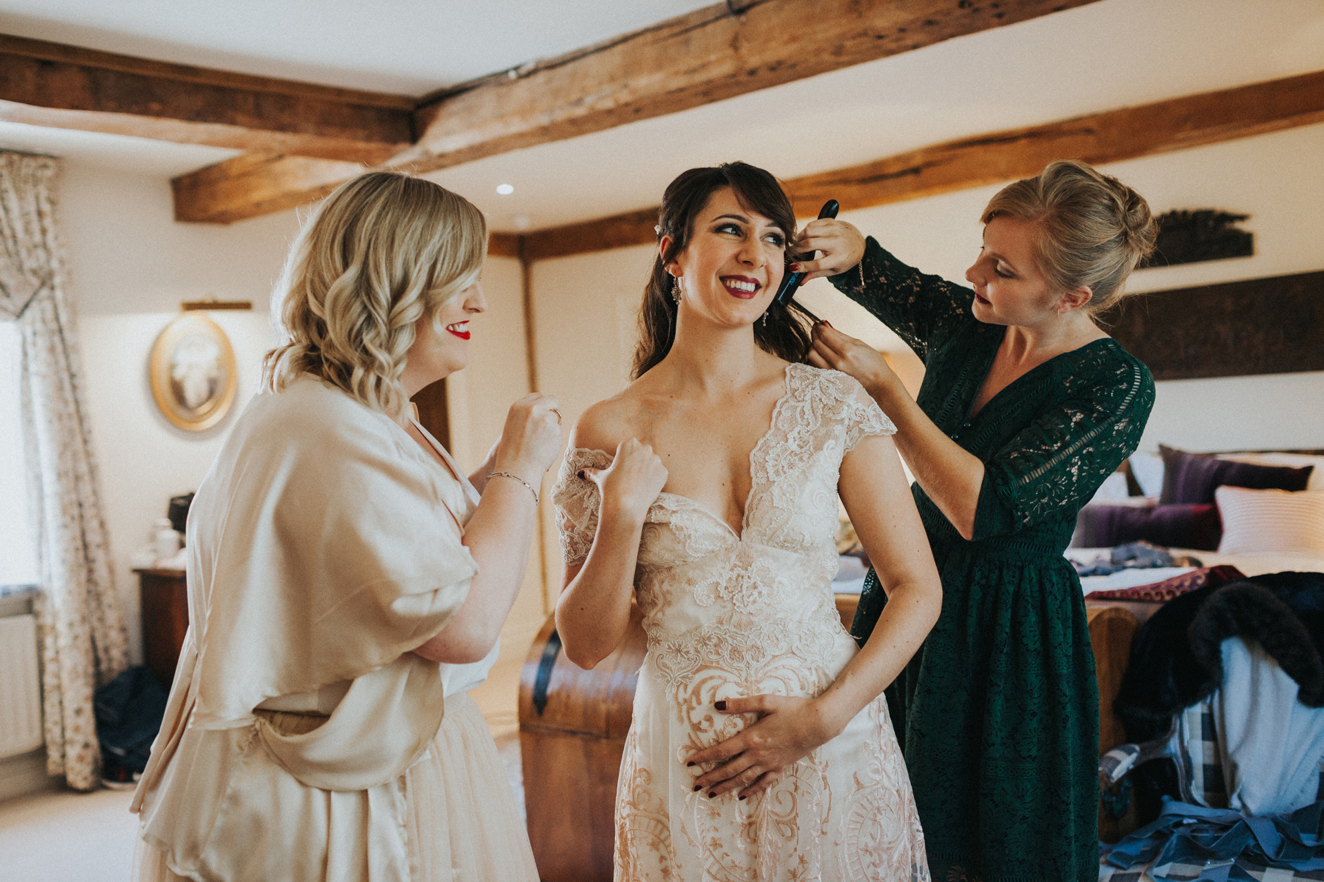 Bride laughing as bridesmaids and friends fuss over her. 